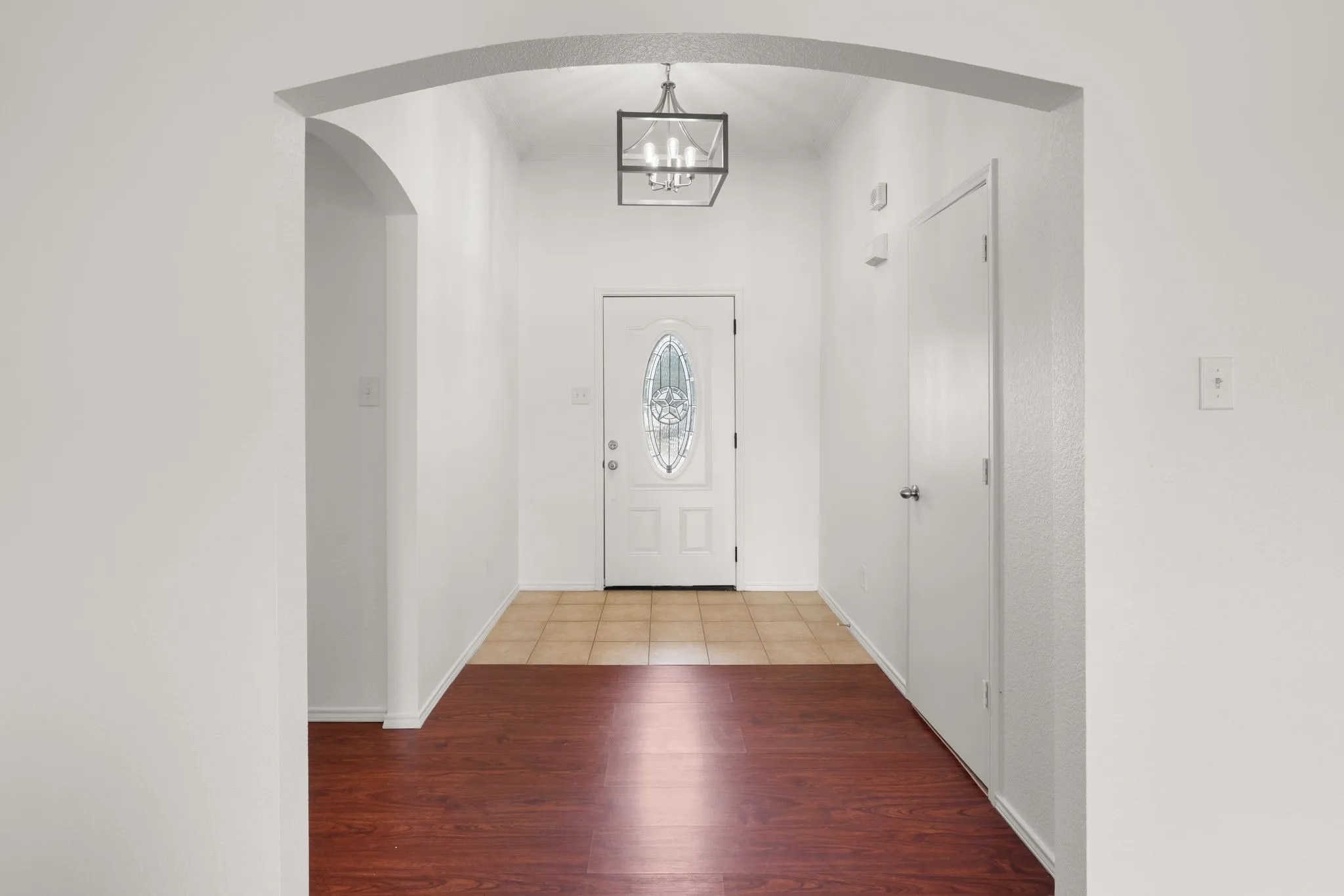 Entryway featuring a decorative glass front door, overhead geometric pendant light, and an arched doorway