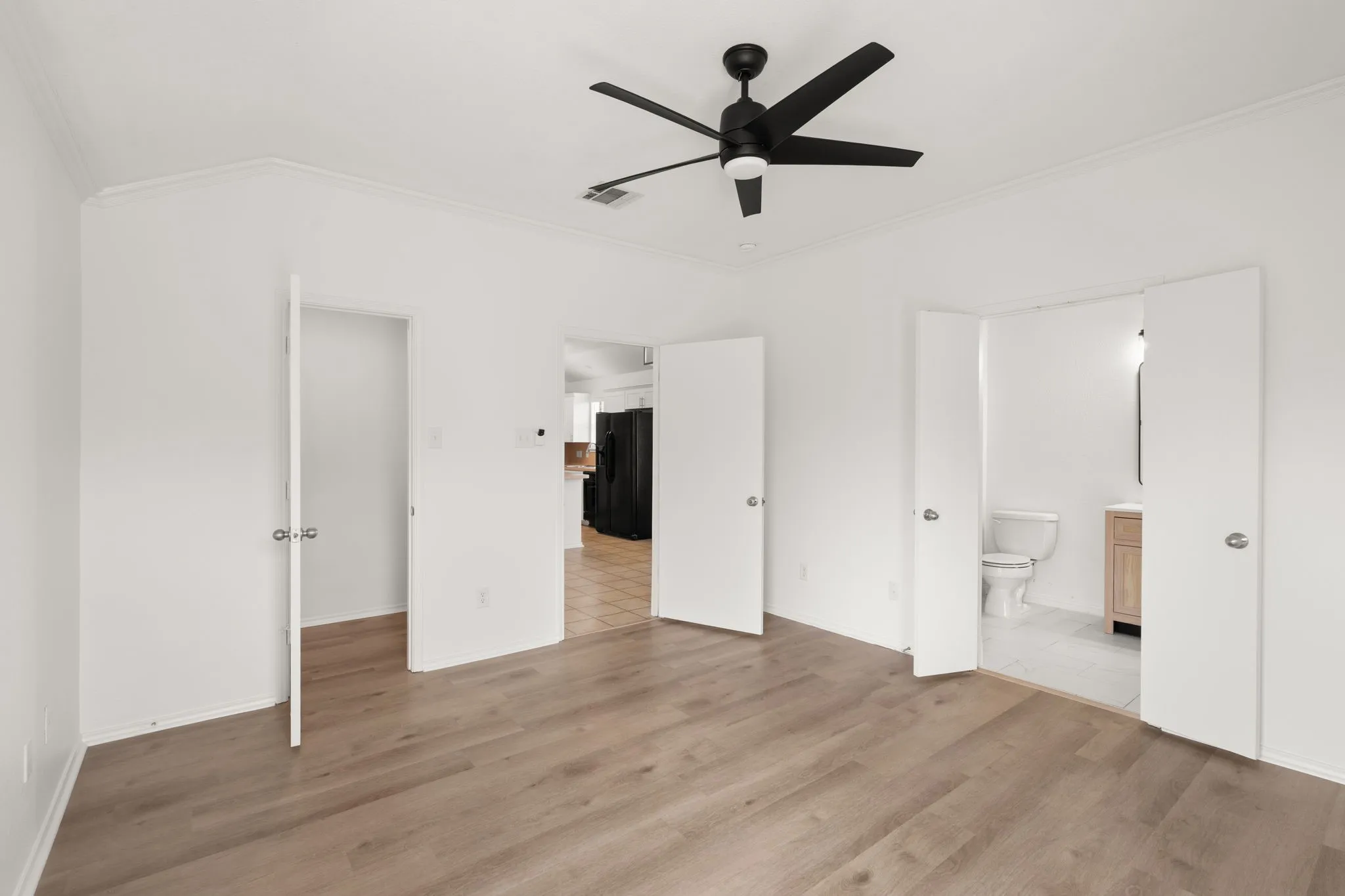 Neutral-toned wood-finish flooring complements white walls and crown molding