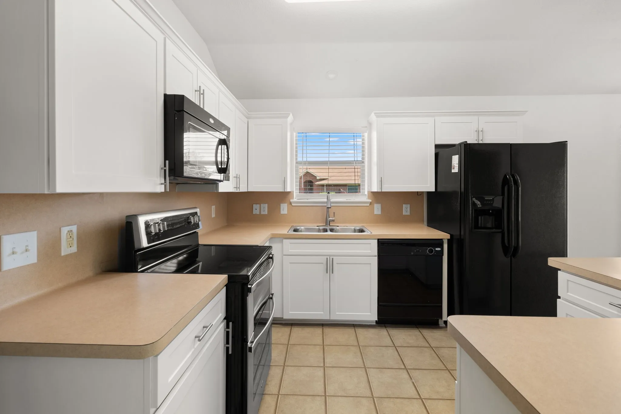 Contemporary kitchen featuring white cabinetry, light-toned countertops, and full-size black appliances