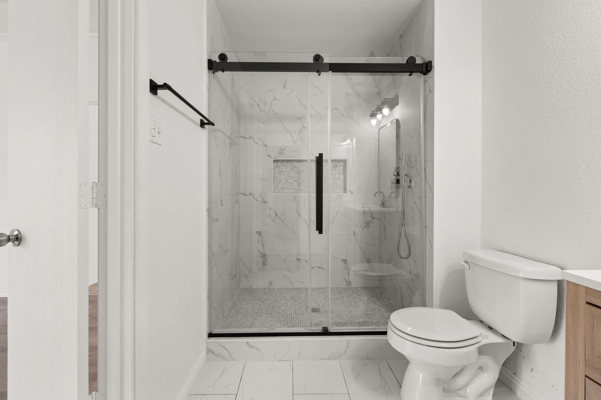 Spacious shower enclosure with clear glass doors and matte black hardware