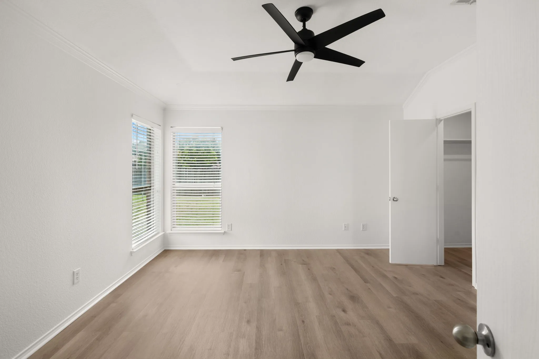 Room featuring wood-finish flooring, a contemporary ceiling fan, and white walls with baseboards