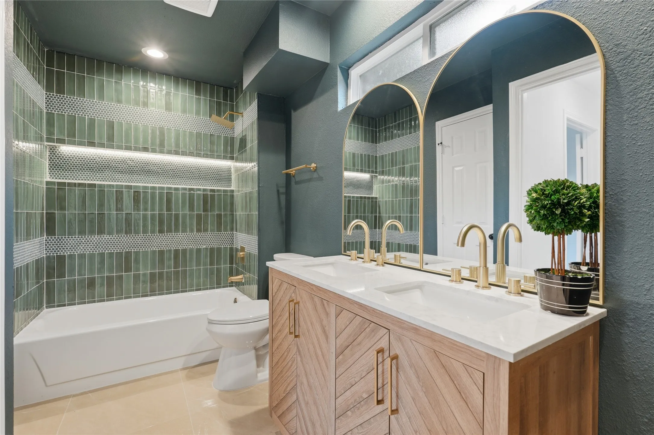 Double vanity with dual undermount sinks, gold-finish fixtures, and arched mirrors