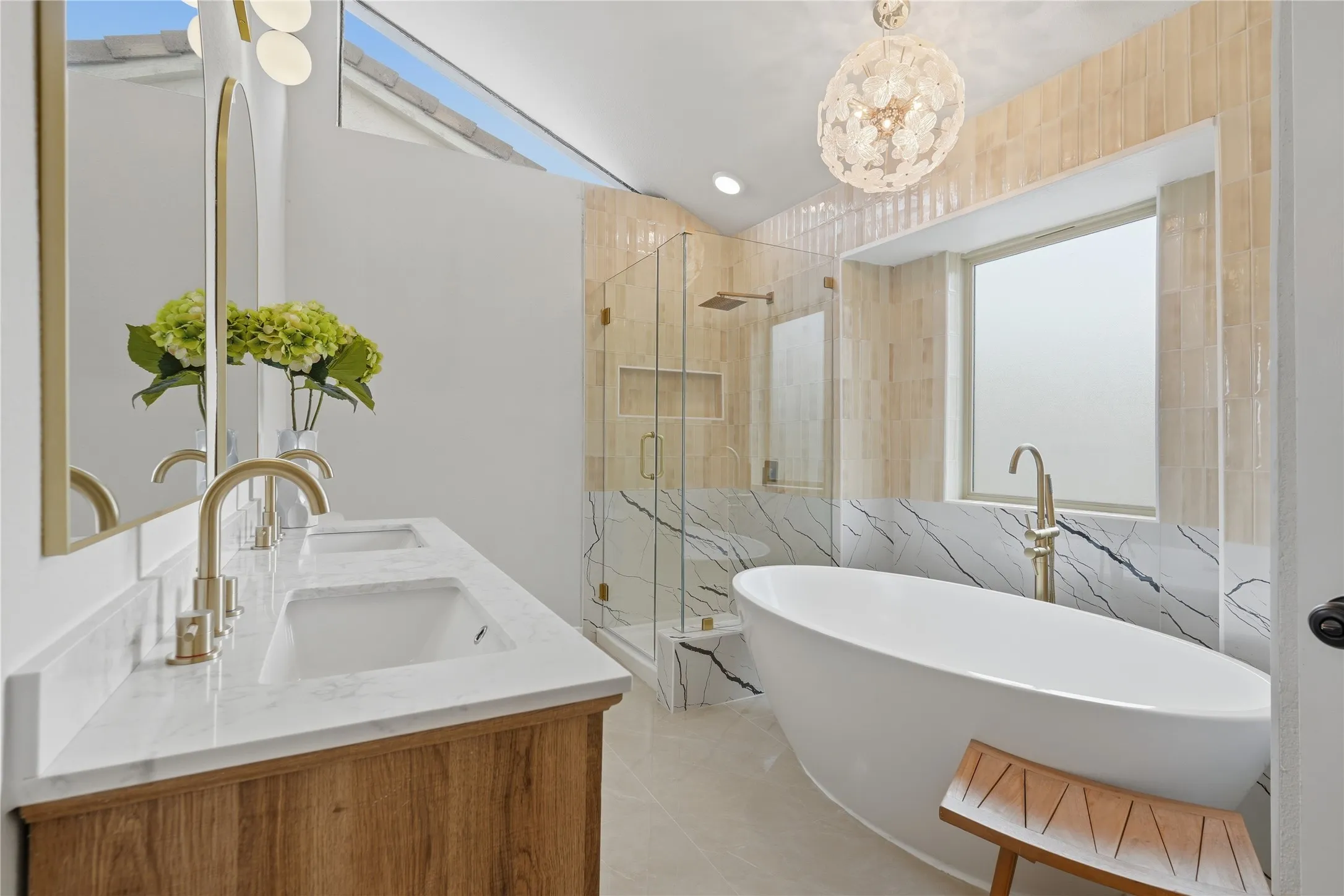 Modern bathroom featuring a freestanding soaking tub, a frameless glass shower enclosure with a built-in niche, and a double vanity with a wood-finish base and light-toned countertop