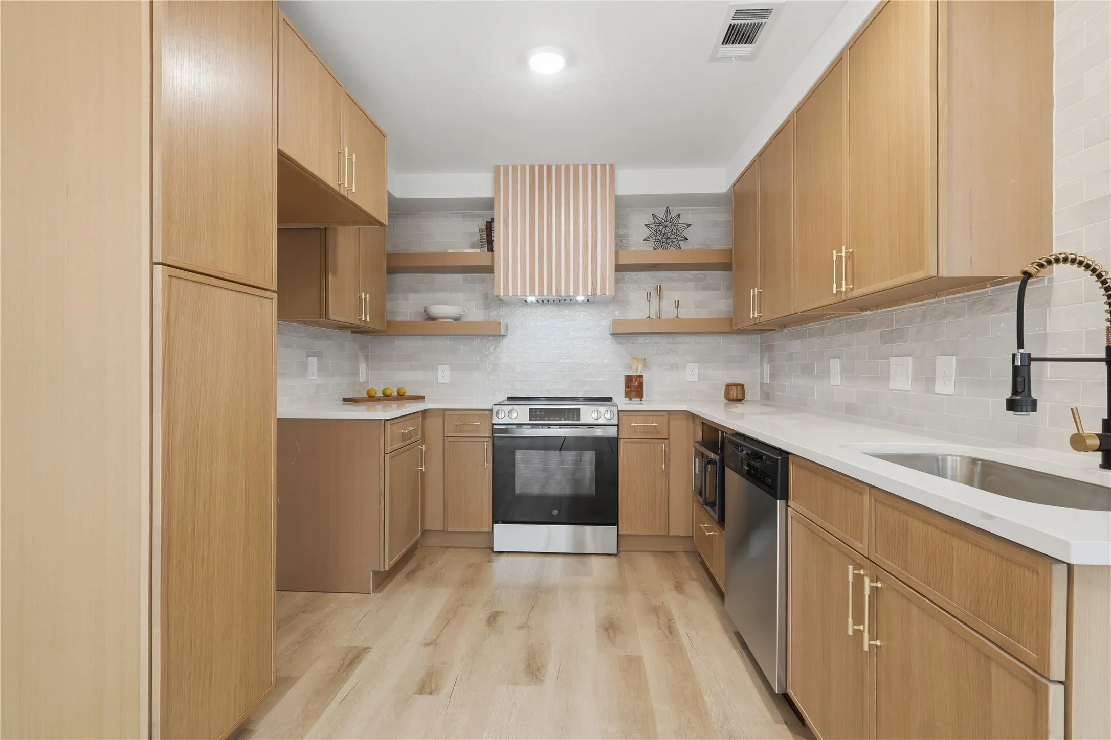 Modern kitchen featuring wood-finish cabinetry, stainless steel appliances, a white countertop, and a tiled backsplash