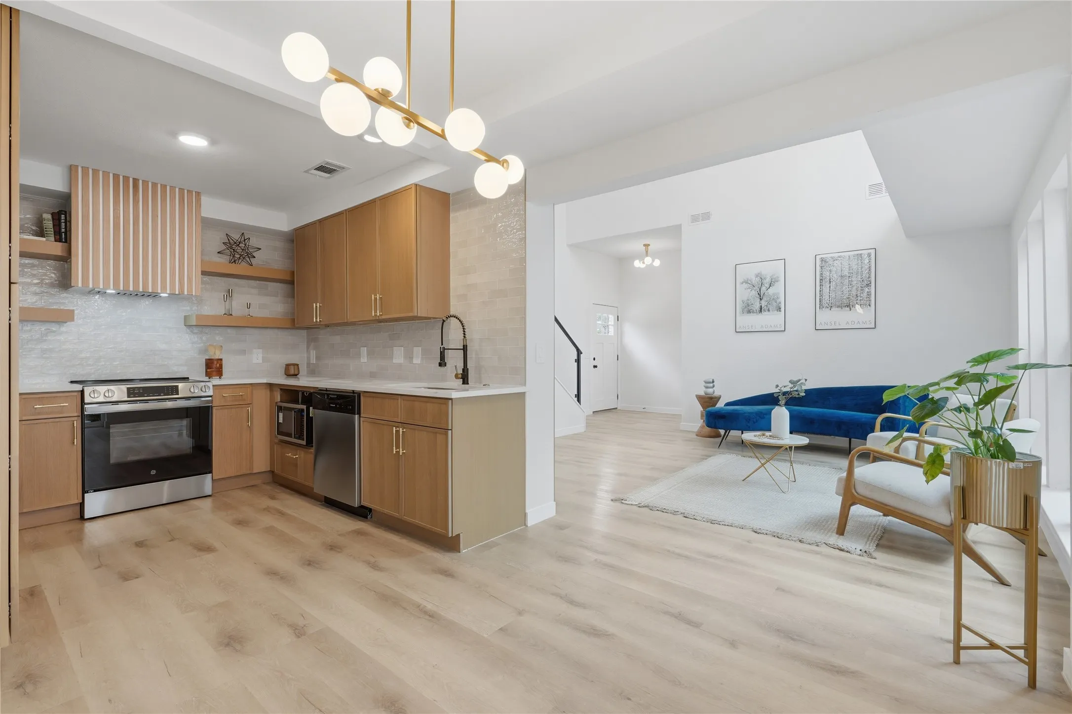 Open-concept kitchen and living area featuring wood-finish flooring, recessed lighting, and a modern gold-toned chandelier