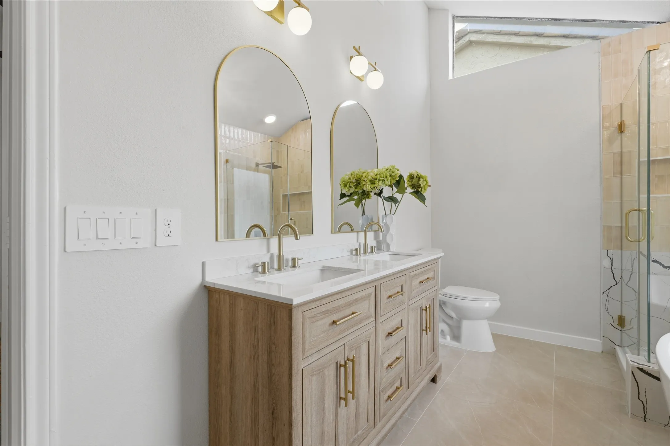 Double vanity with wood-finish cabinetry, gold-tone hardware, and white countertop