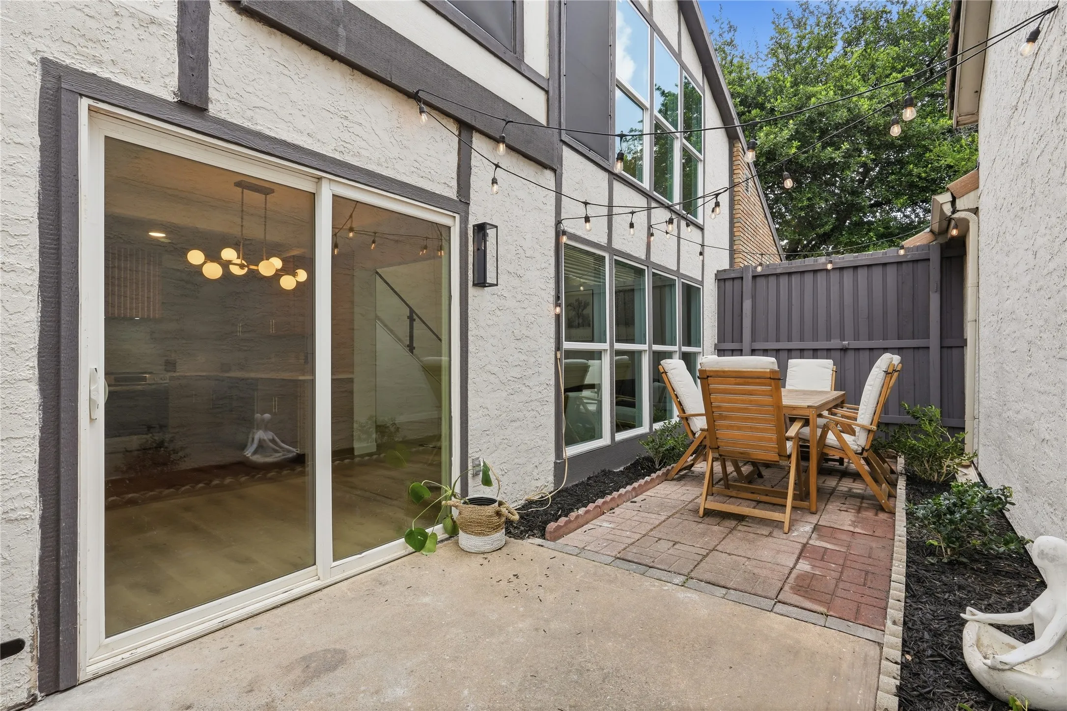 Outdoor patio area featuring a brick paver section, privacy fencing, and a concrete pad