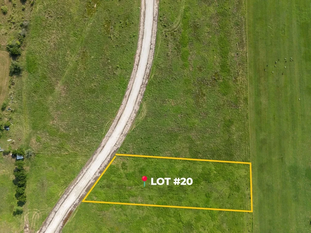 Expansive green lot bordered by a curving unpaved road