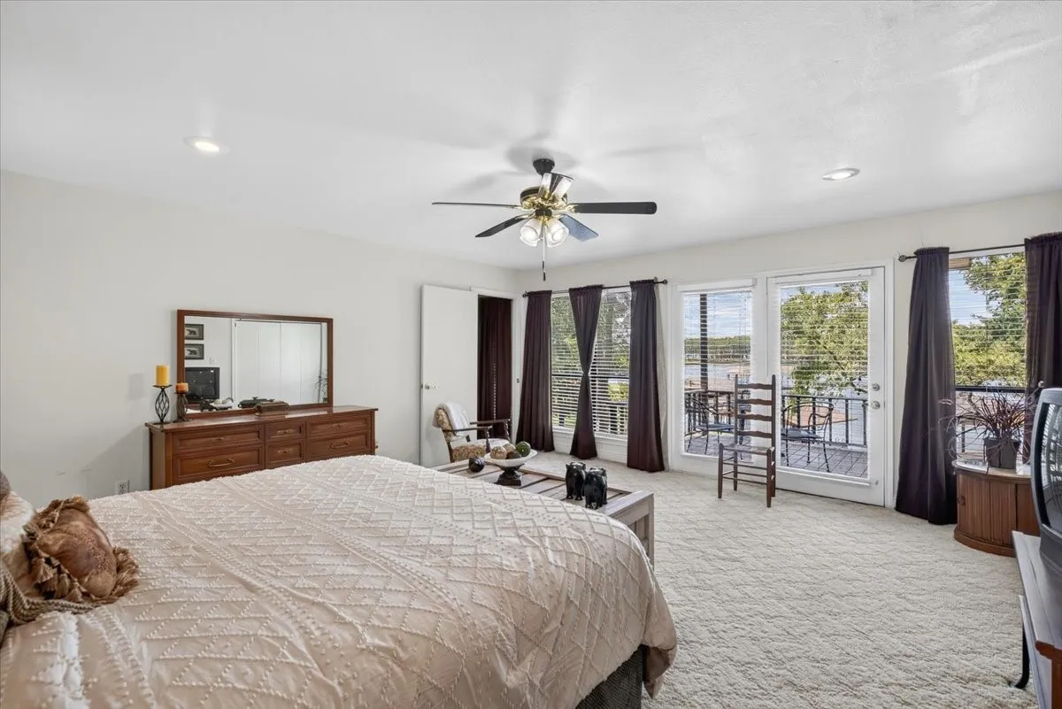 2nd floor Primary Bedroom with bath and featuring multiple large windows and a glass paneled door opening to a lakeside balcony.