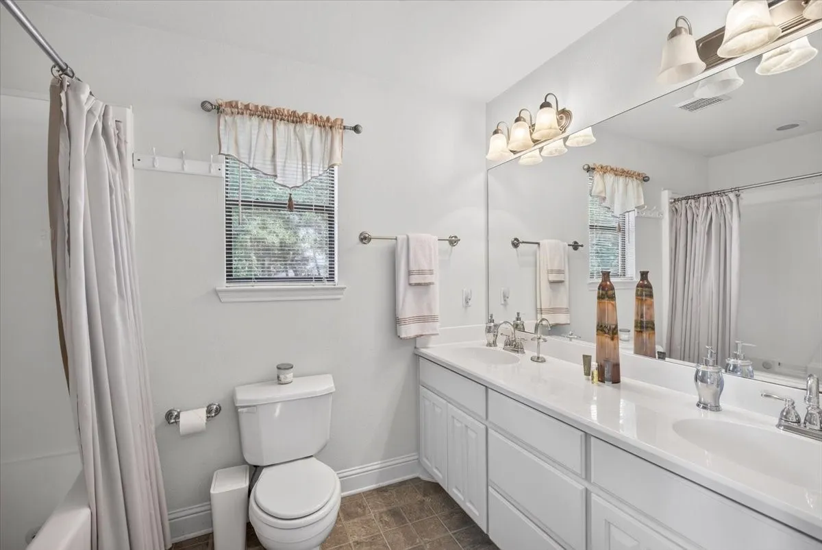 Second floor bath featuring a double vanity with white cabinetry, integrated sinks, brushed nickel fixtures, a large wall-mounted mirror, and tub-shower.