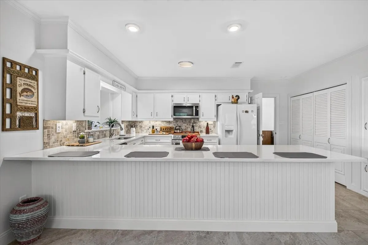 Kitchen featuring an expansive center island with beadboard paneling, quartz counters, and integrated breakfast bar with unlimited storage.