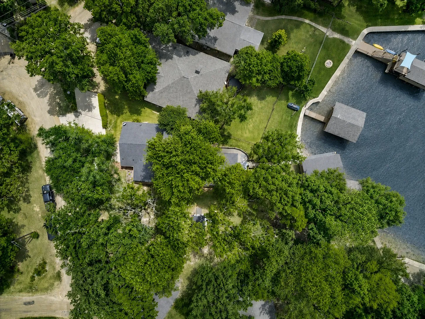 Aerial perspective of a lakeside property in a cove off of open water featuring extensive tree coverage, direct water access, and amazing sunset views.