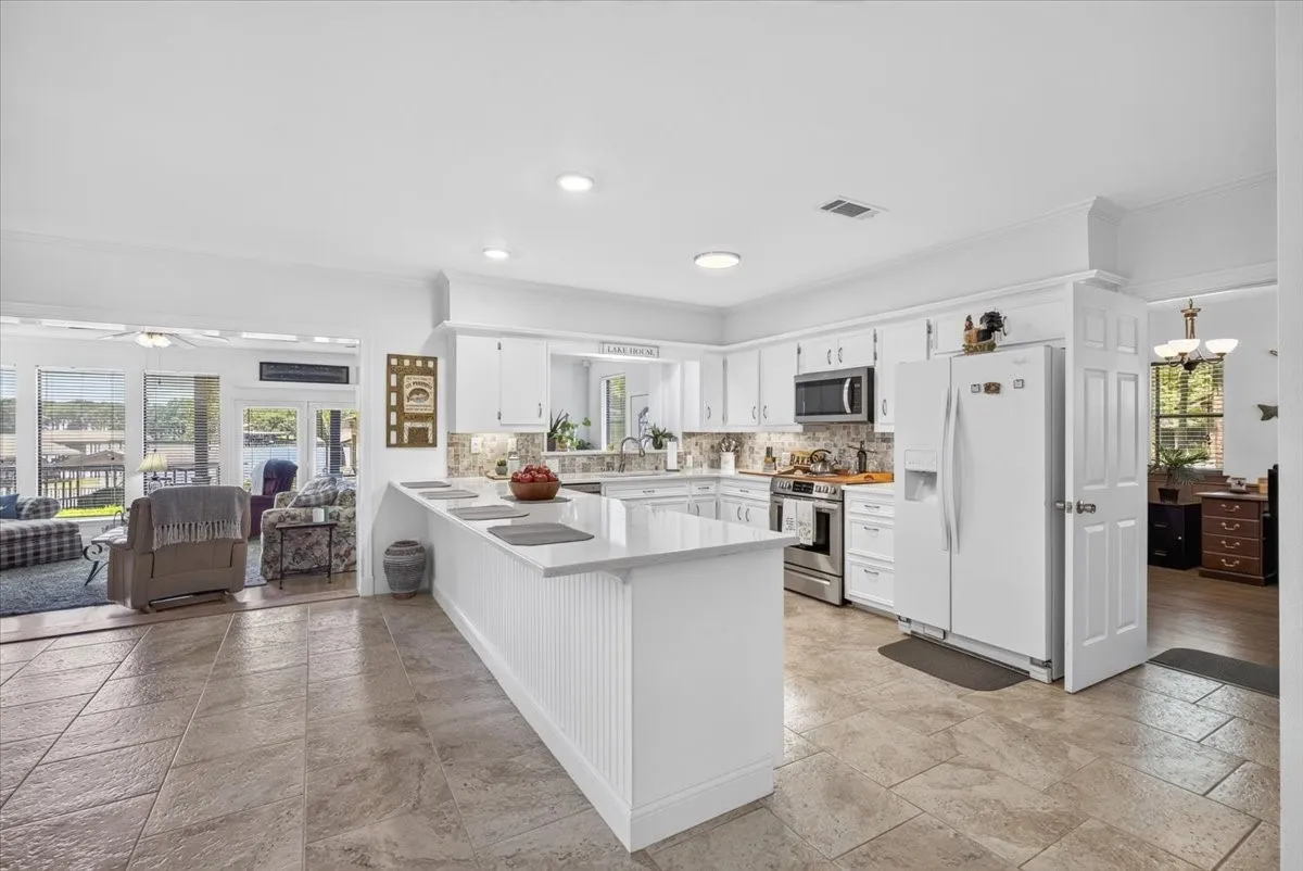 Kitchen featuring an expansive center island with beadboard paneling, quartz counters, and integrated breakfast bar with unlimited storage.