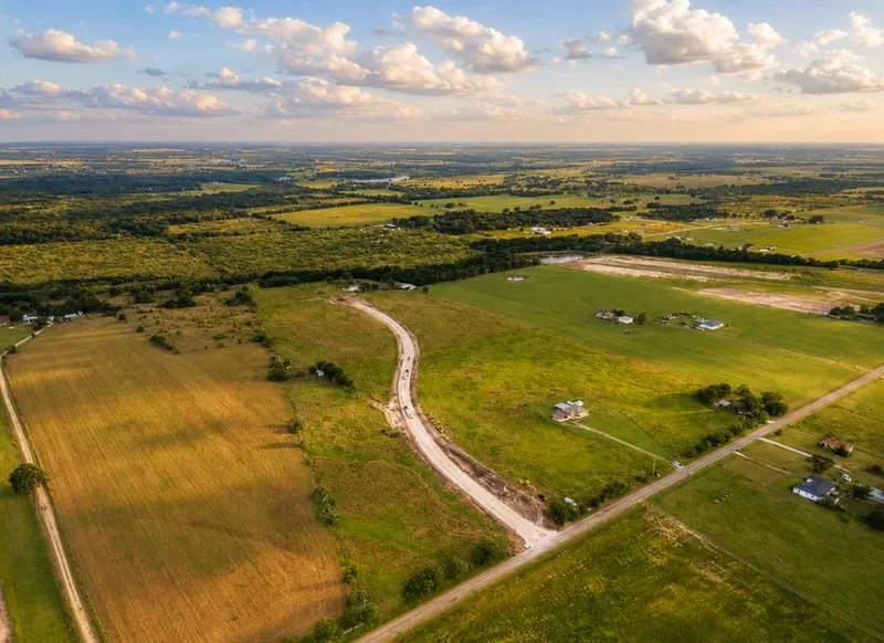 Expansive rural landscape featuring a mix of open fields, wooded areas, and scattered residential properties