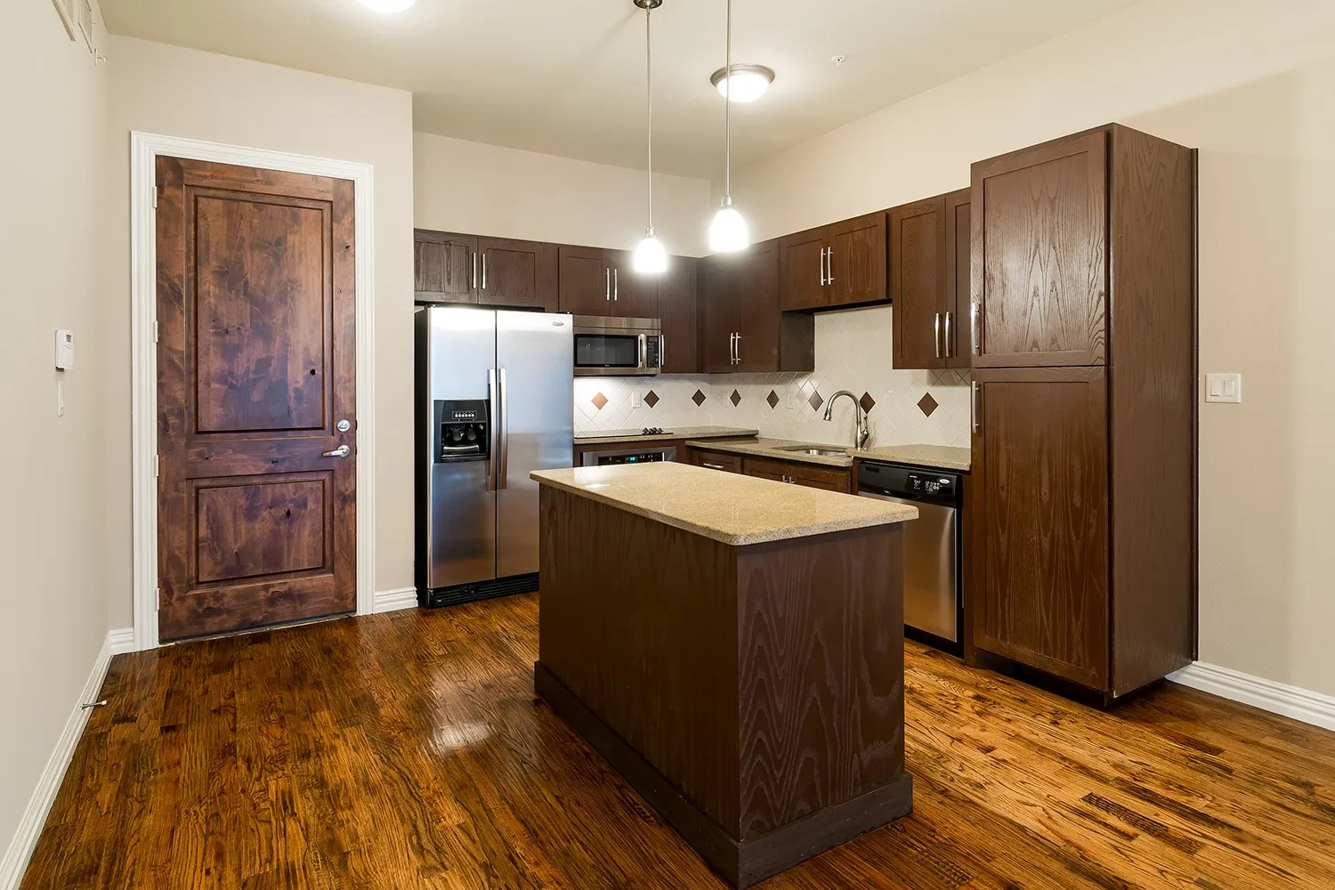 Kitchen featuring stainless steel appliances, pendant lighting, dark wood finish cabinetry, a center island, and decorative backsplash