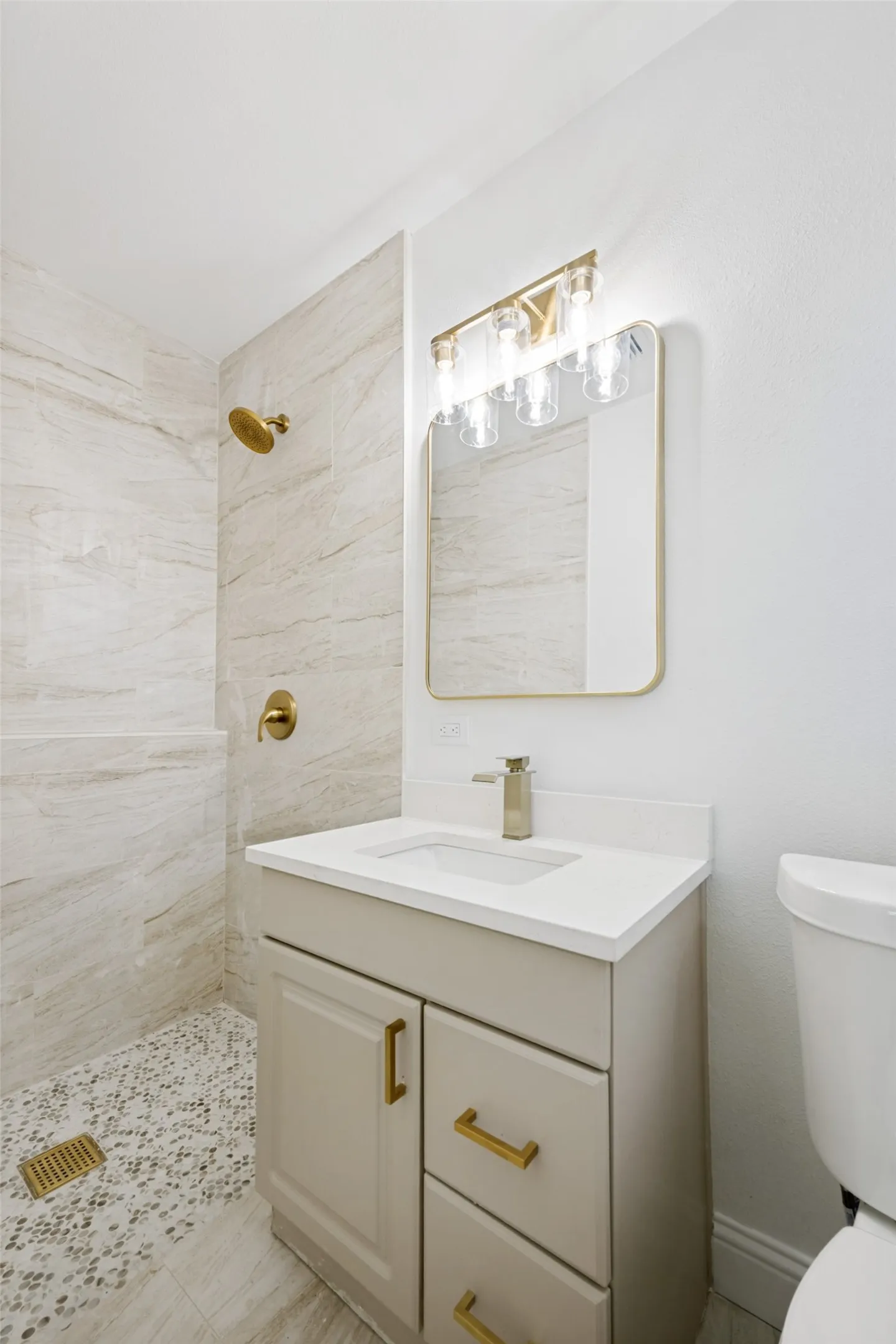 Bathroom featuring a beige vanity with gold-tone hardware, a white countertop, and an integrated sink