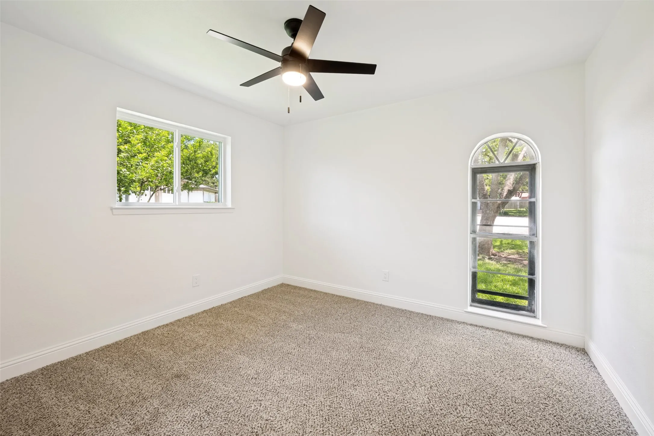 Interior room featuring a contemporary ceiling fan with integrated lighting, a rectangular window, and an arched window