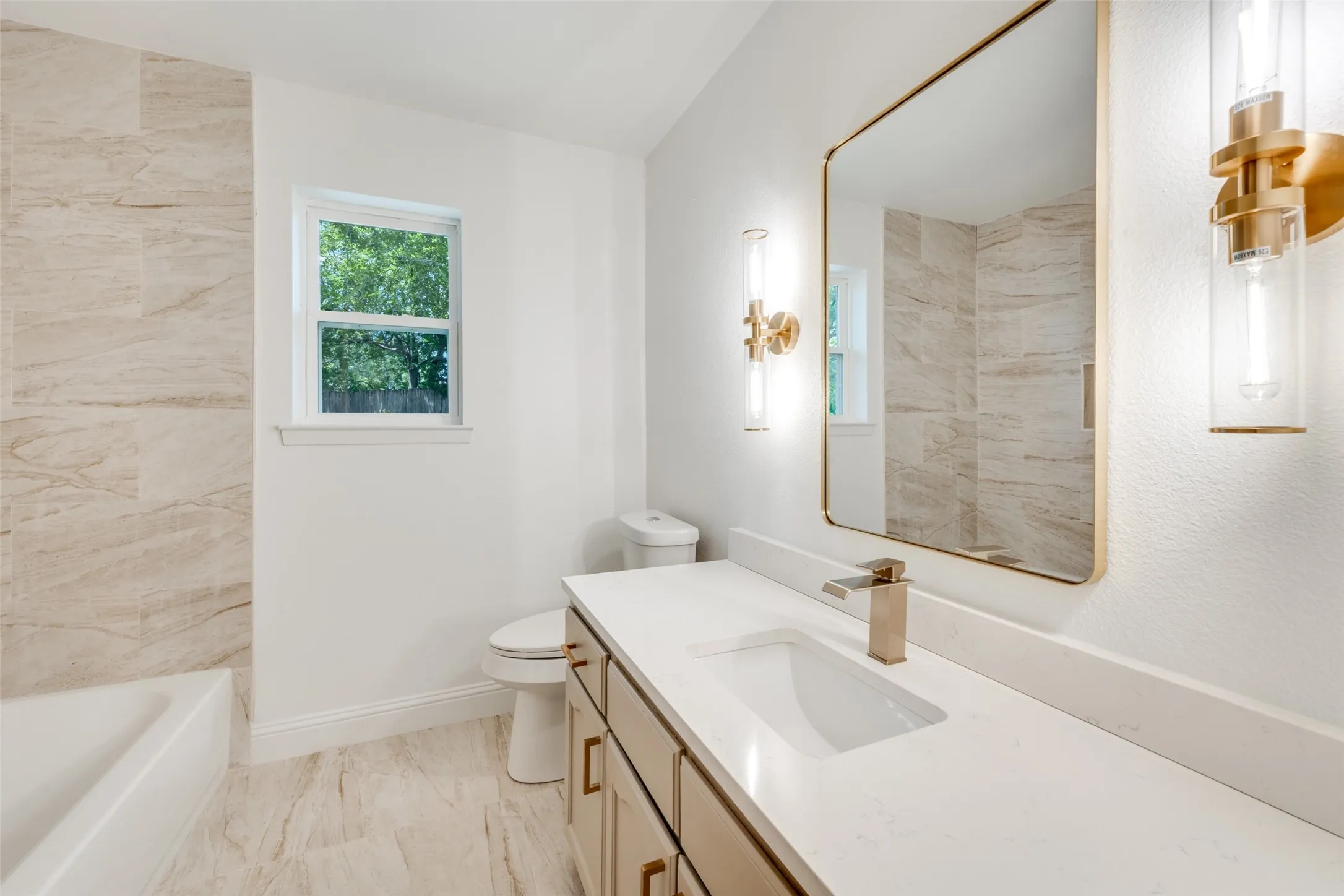 Bathroom featuring a full vanity with a white countertop and undermount sink, brass-finish faucet, and coordinating cabinet hardware