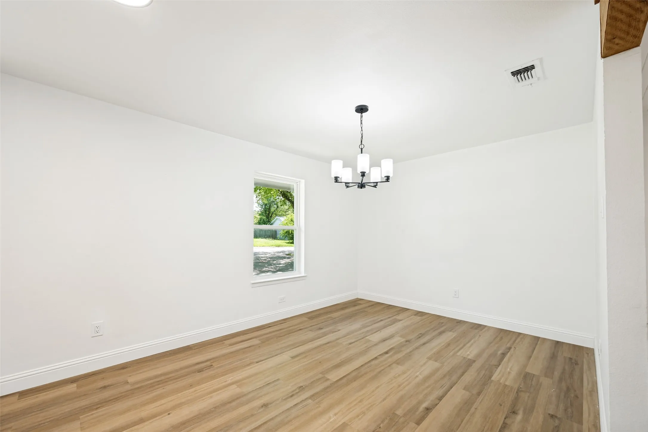 Room with wood-finish flooring, white baseboards, and a single window