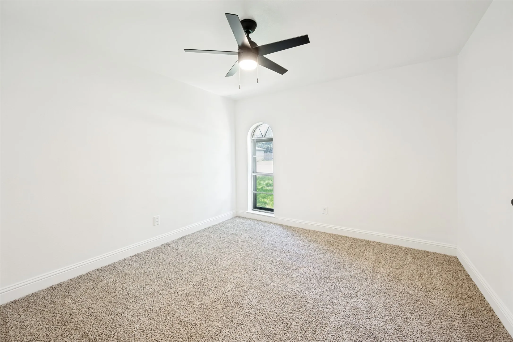 Bright room featuring a recessed arched window, neutral carpeting, and a contemporary ceiling fan with integrated lighting