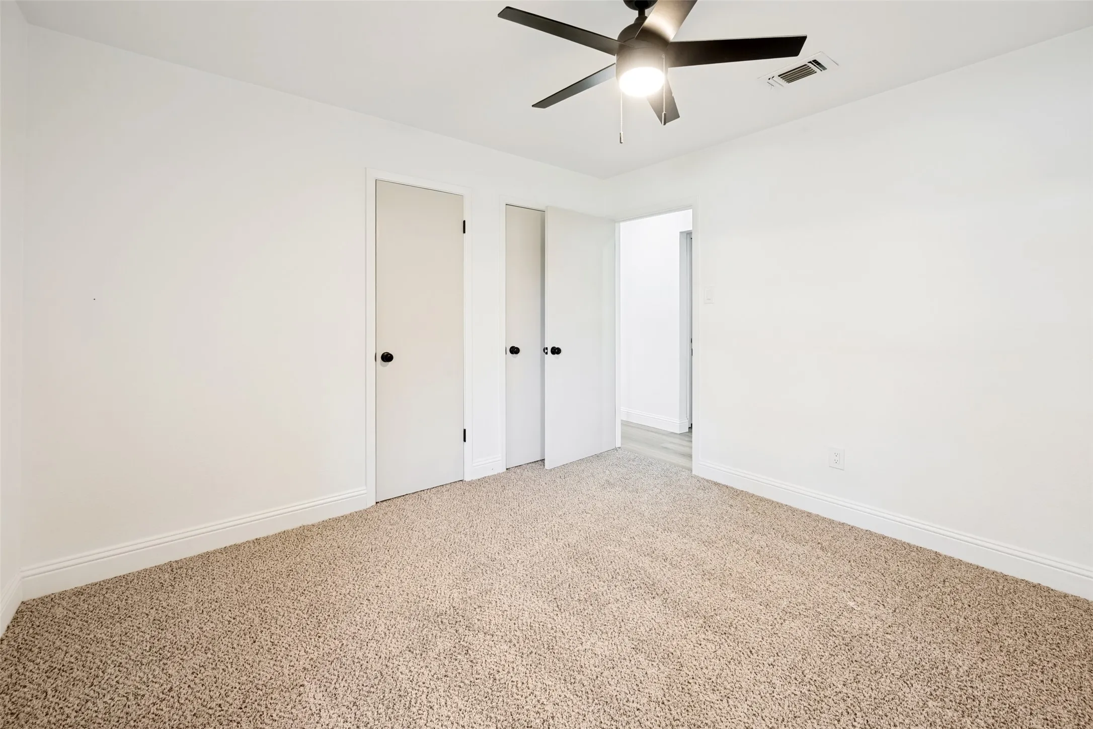 Expansive room featuring light-colored carpeting, white baseboards, and bright white walls