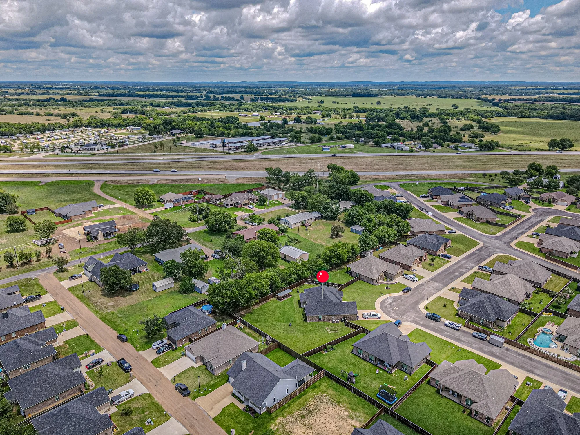 Aerial perspective of a residential neighborhood featuring single-story homes with dark shingled roofs and fenced yards