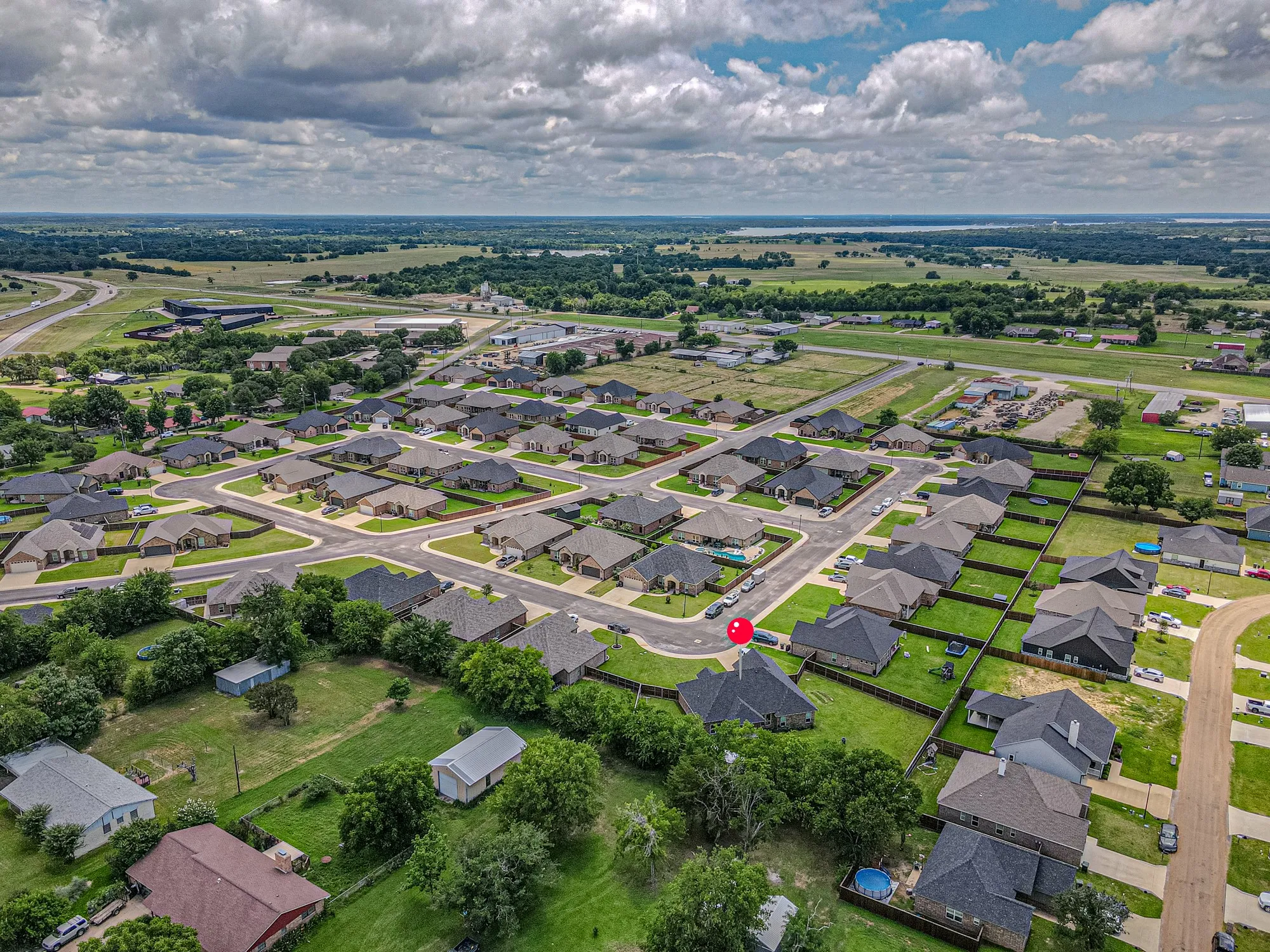 Aerial view of a residential neighborhood with single-story homes and a visible lake in the distance