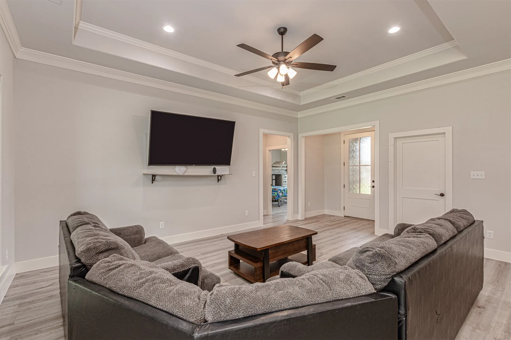 Living area featuring a tray ceiling with recessed lighting and a ceiling fan