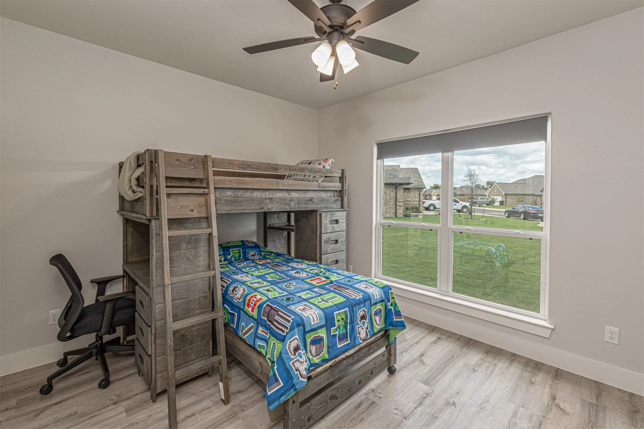Bright room featuring a large window, a ceiling fan, light wood-finish flooring, and white baseboards