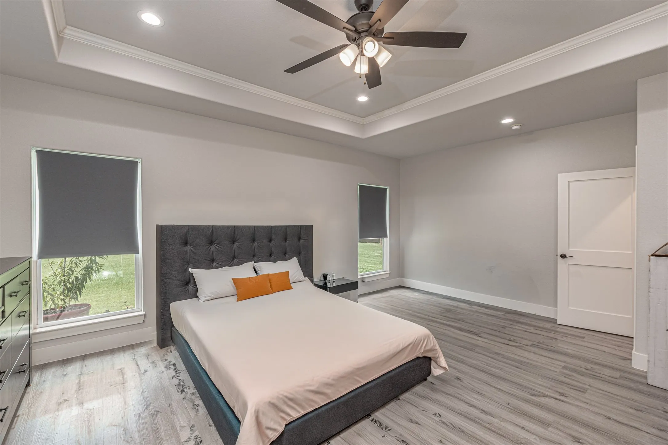 Spacious room featuring tray ceilings, recessed lighting, and a ceiling fan
