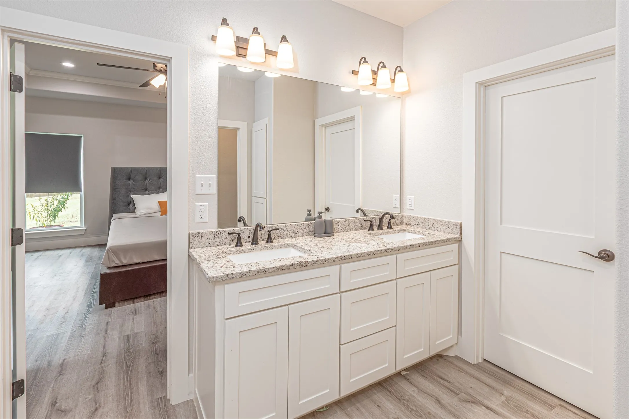 Double vanity with white cabinetry and light granite-style countertops