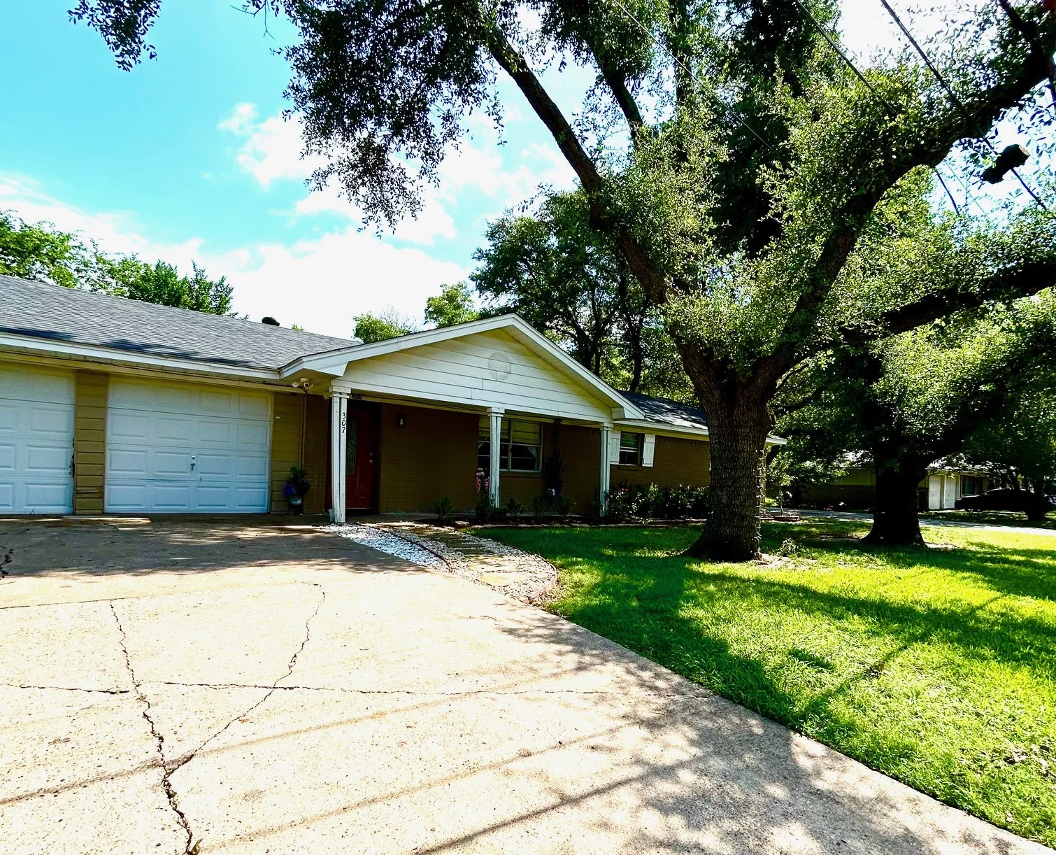 Single story home featuring a front yard, a garage, driveway, and covered porch