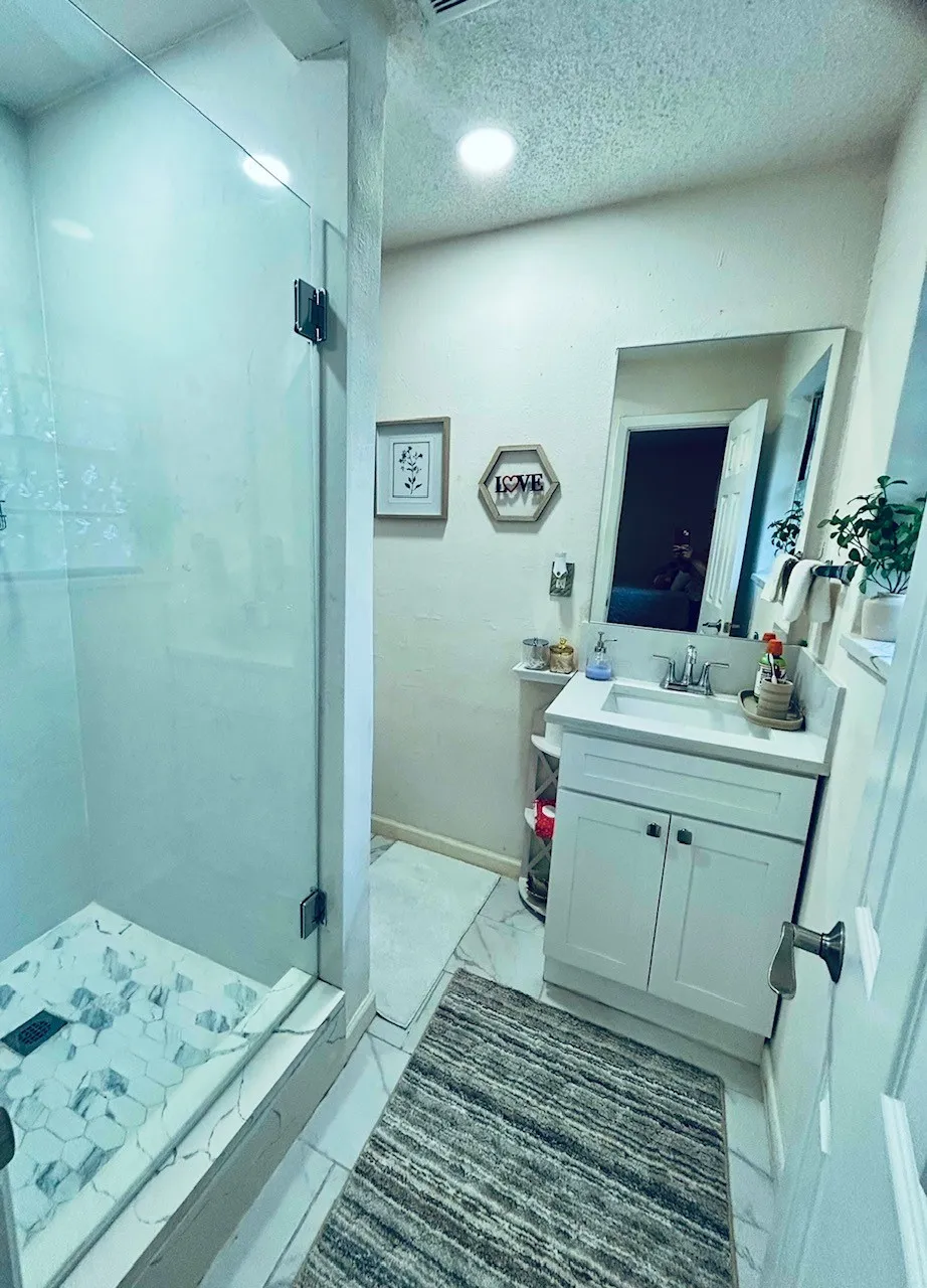 Bathroom with a stall shower, vanity, marble look tiles, and a textured ceiling