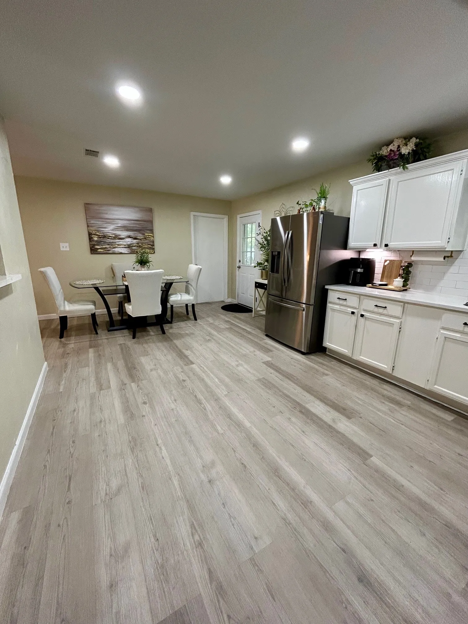 Kitchen featuring stainless steel refrigerator with ice dispenser, light wood-style flooring, white cabinetry, recessed lighting, and light countertops
