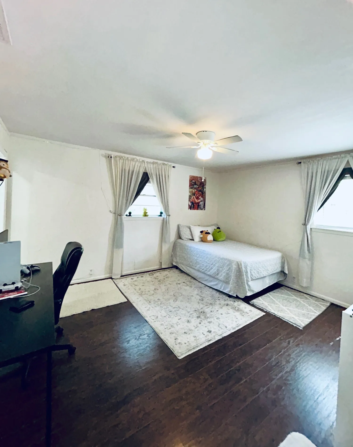 Bedroom featuring hardwood / wood-style floors, multiple windows, ceiling fan, and a desk
