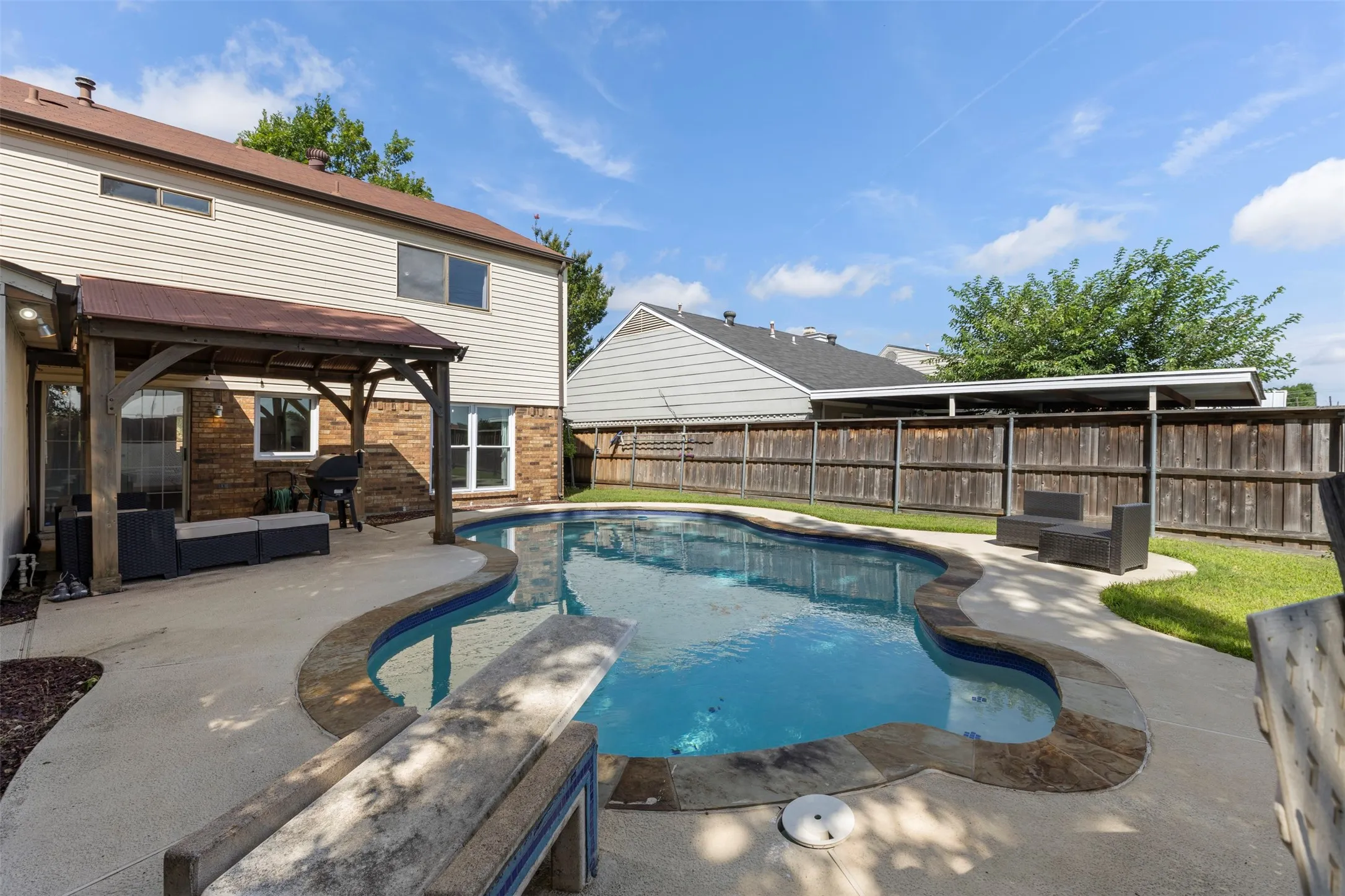 Backyard oasis featuring a freeform swimming pool with concrete surround