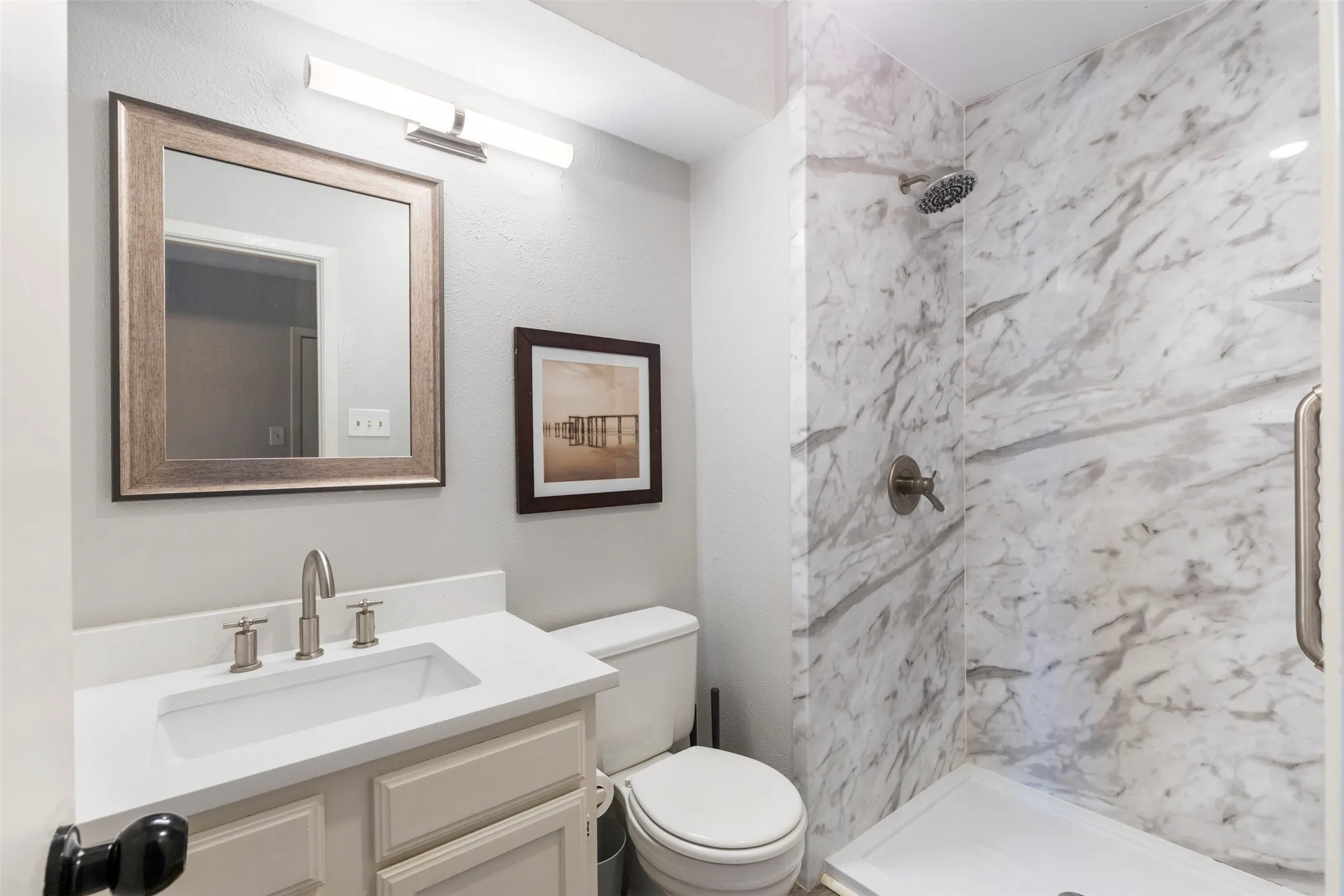 Bathroom featuring a frameless shower with stone-finish walls and a rain shower head