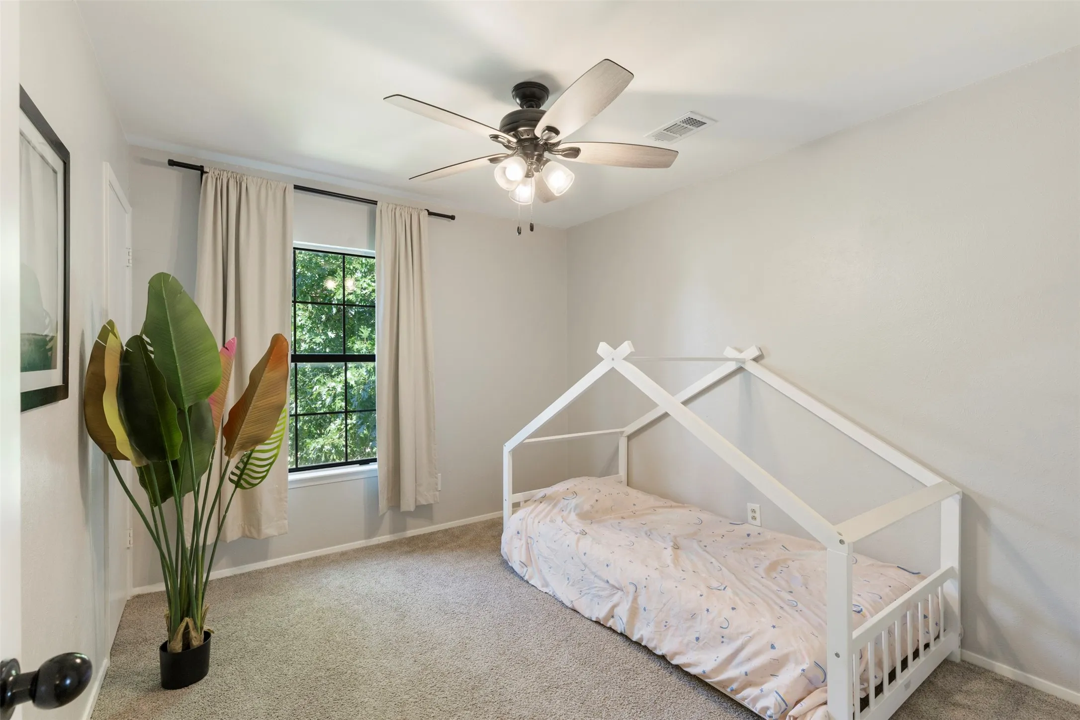 Carpeted room featuring a ceiling fan with integrated lighting, a double-hung window with a verdant exterior, and light-colored walls
