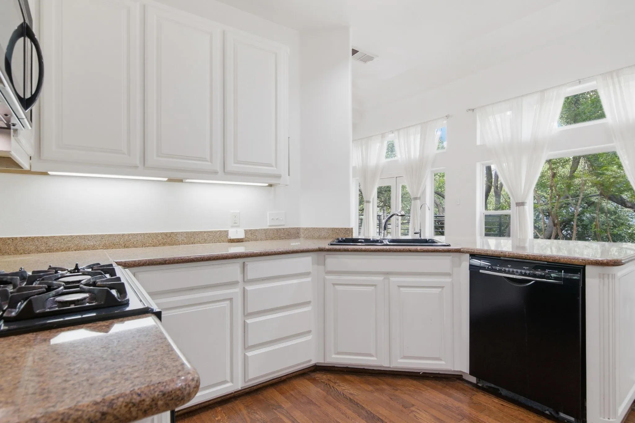 Kitchen featuring white cabinetry, light-colored countertops, a black gas range, and a black dishwasher