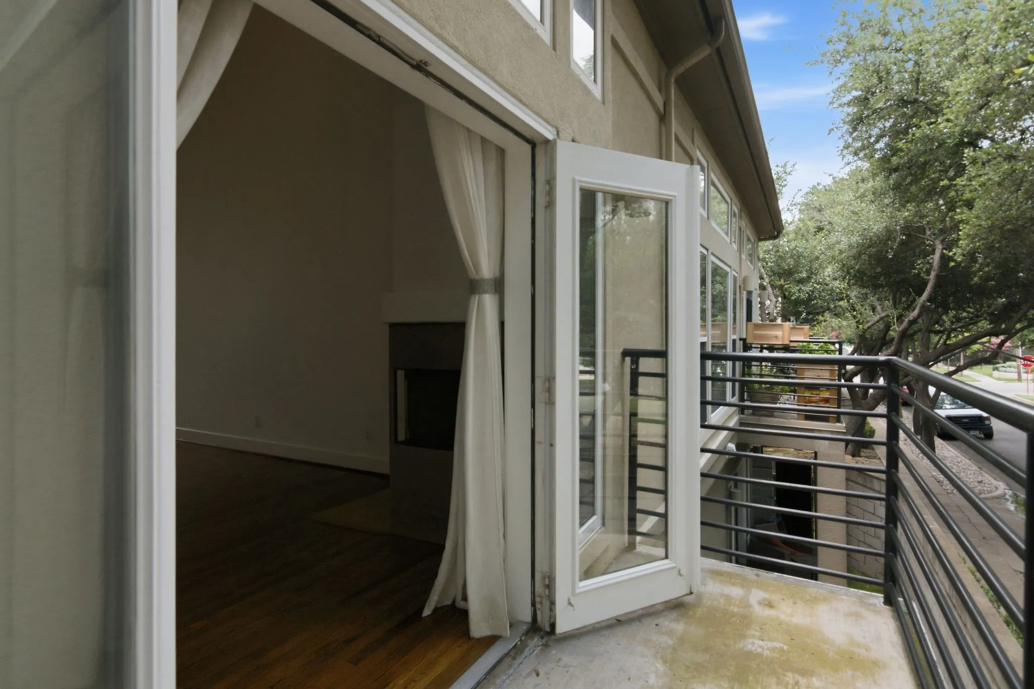 Private balcony with black metal railing, concrete flooring, and double french doors
