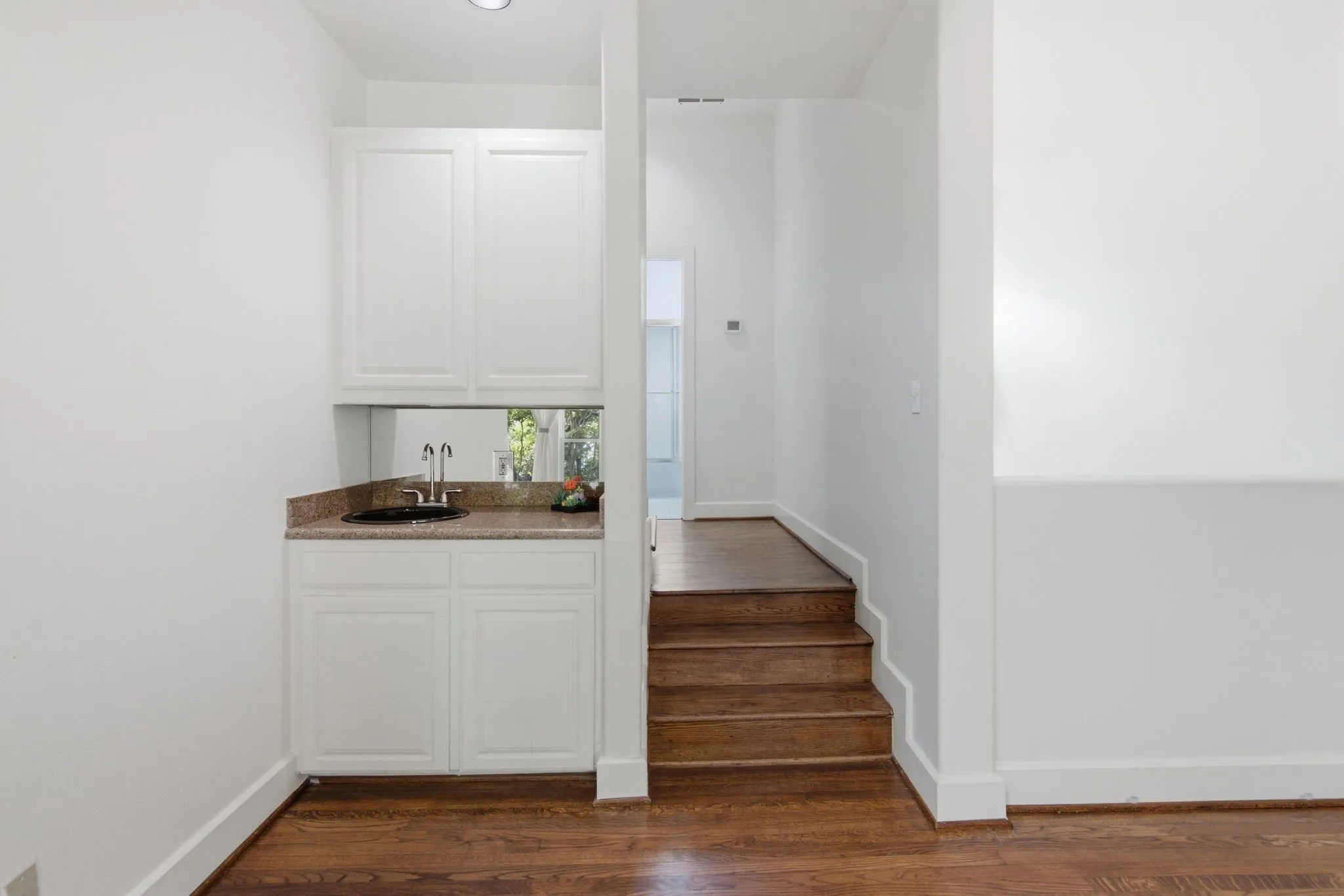 Built-in wet bar featuring white cabinetry, a granite-look countertop, and a circular undermount sink