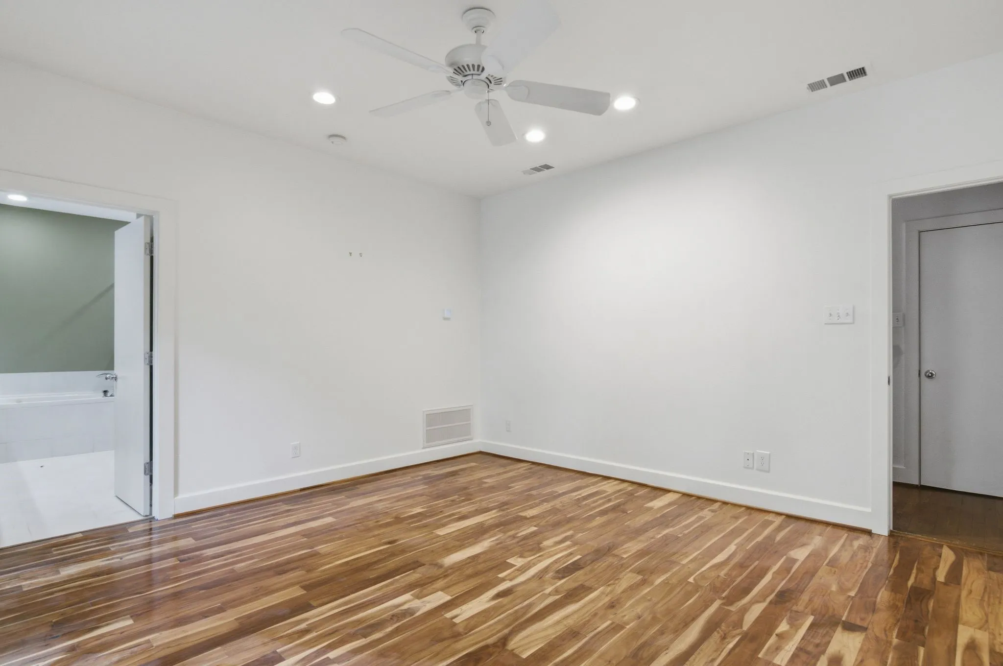 Spacious room featuring wood-finish flooring, recessed lighting, and a ceiling fan