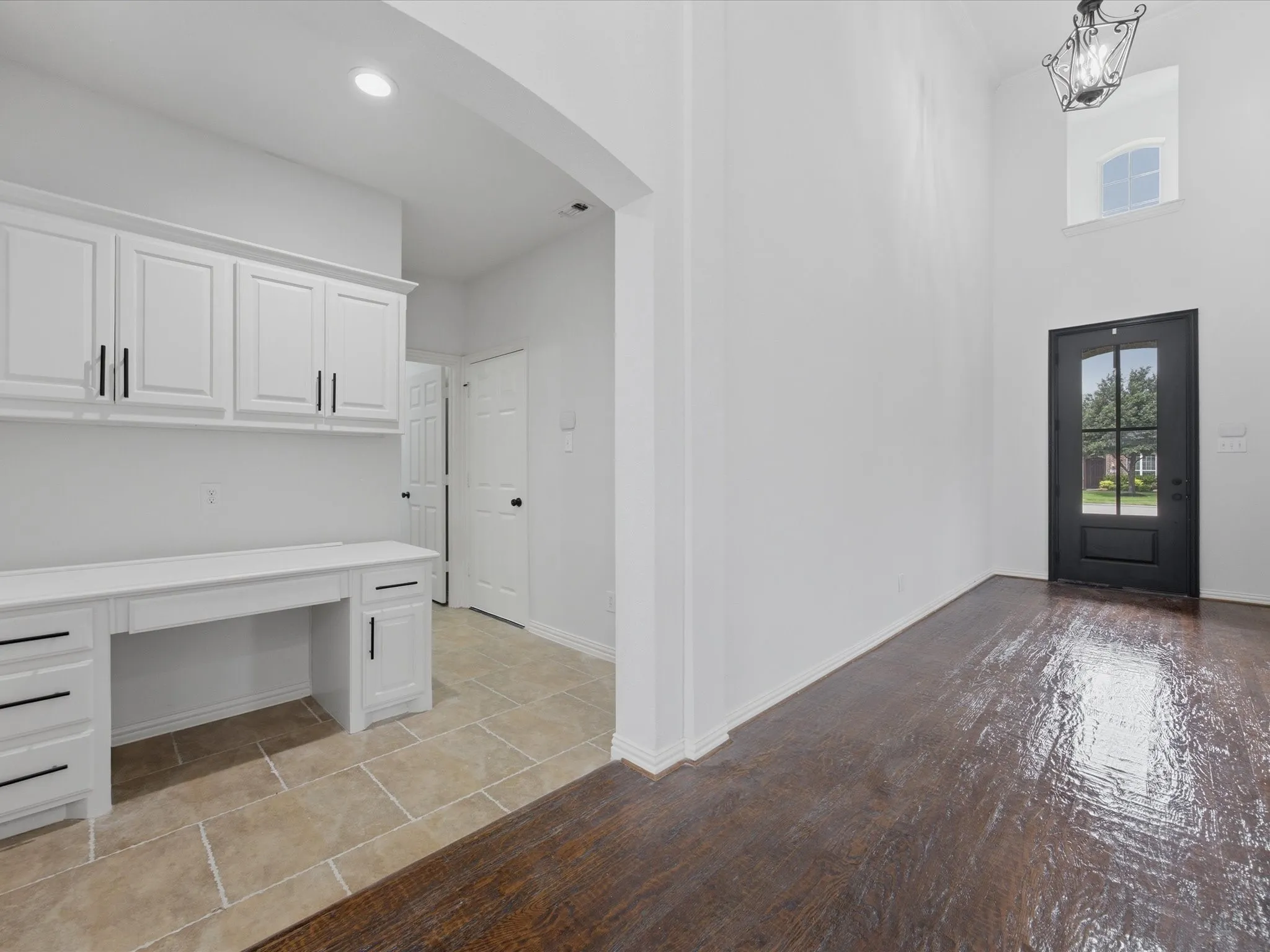 High ceilings with a decorative chandelier and a prominent dark-framed entry door