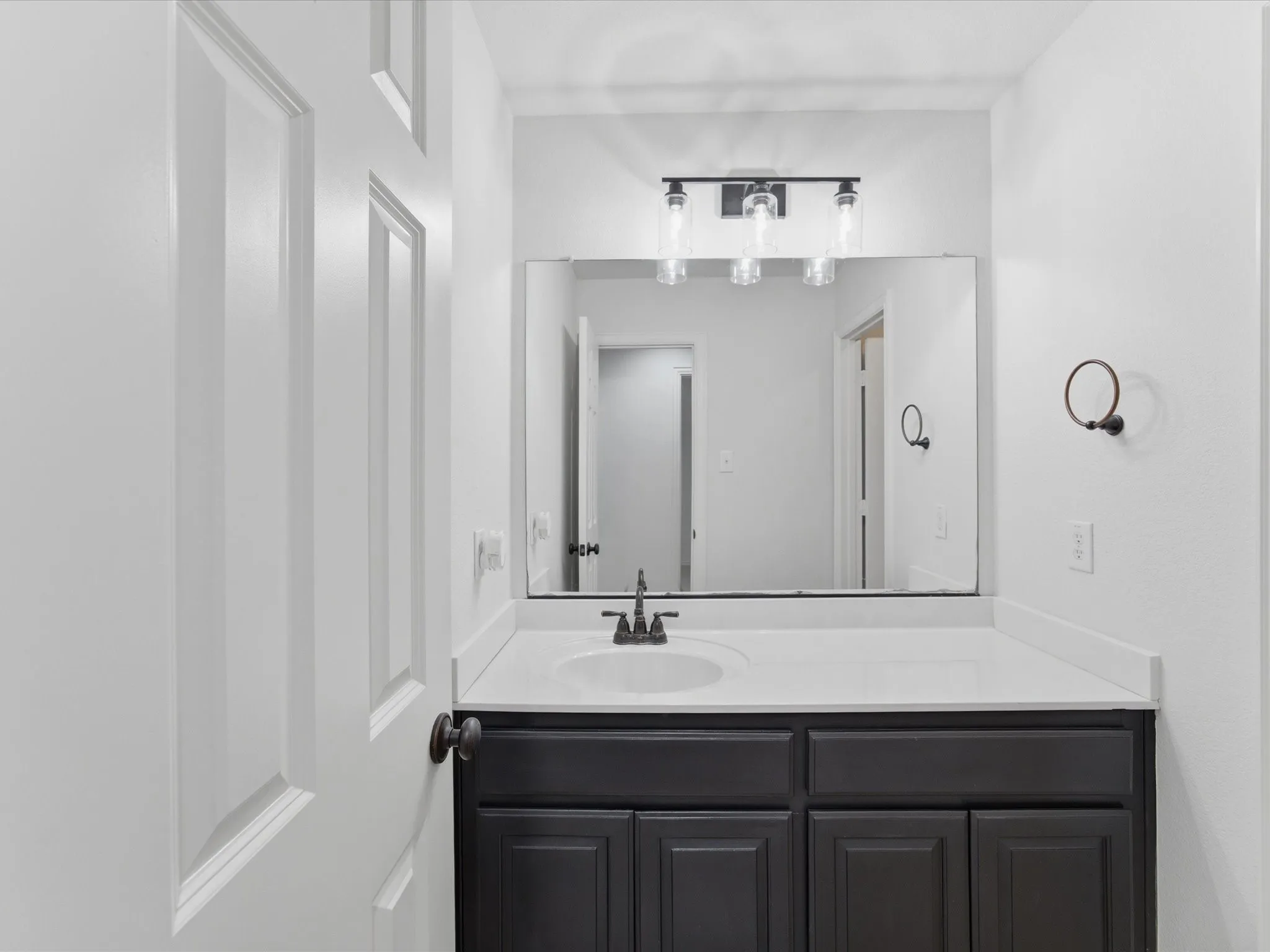 Bathroom vanity with a white countertop and dark cabinetry
