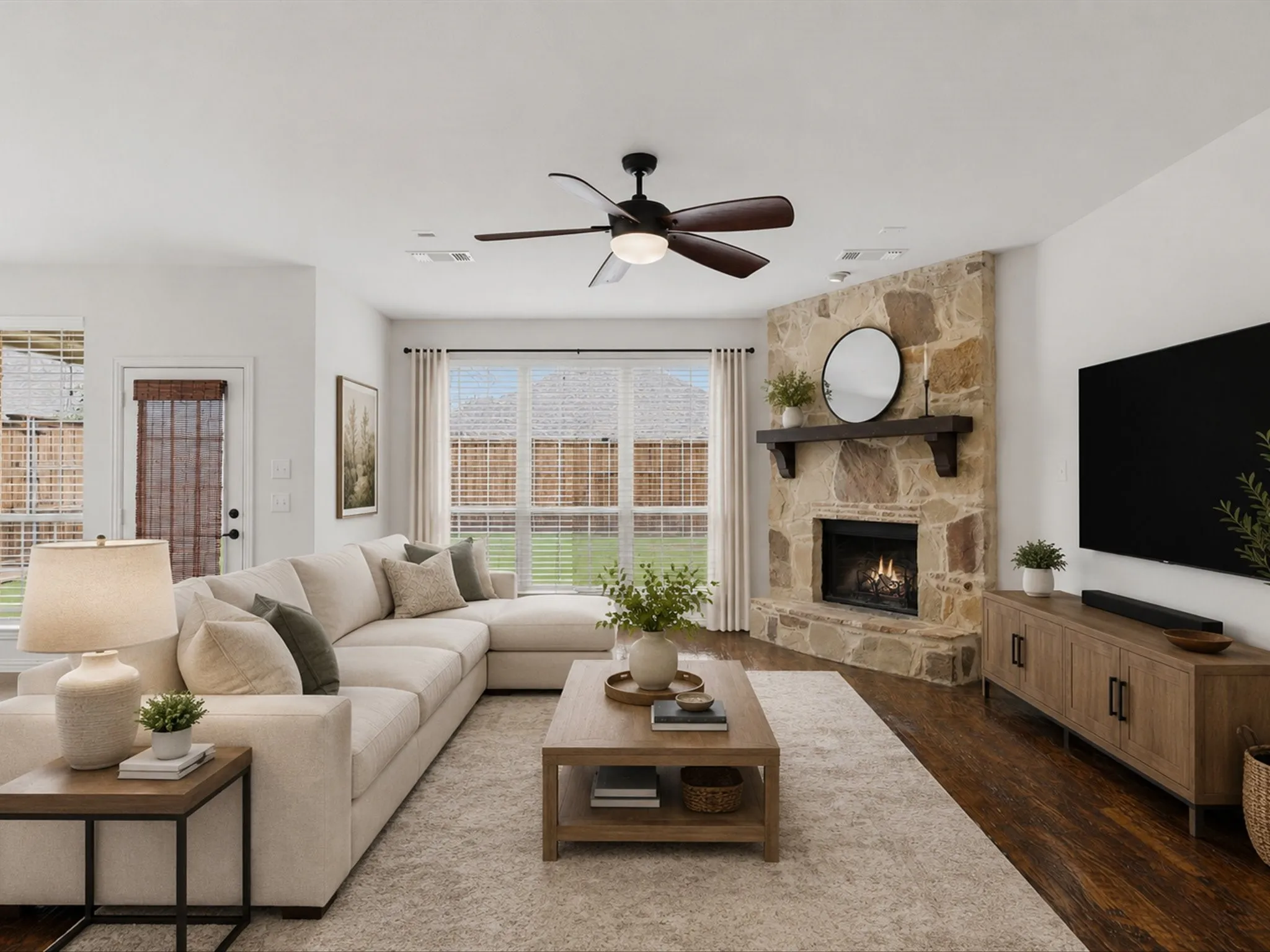 Virtually staged Living room featuring a stone-clad fireplace with a dark wood mantel, wide plank wood-finish flooring, and a ceiling fan with integrated lighting