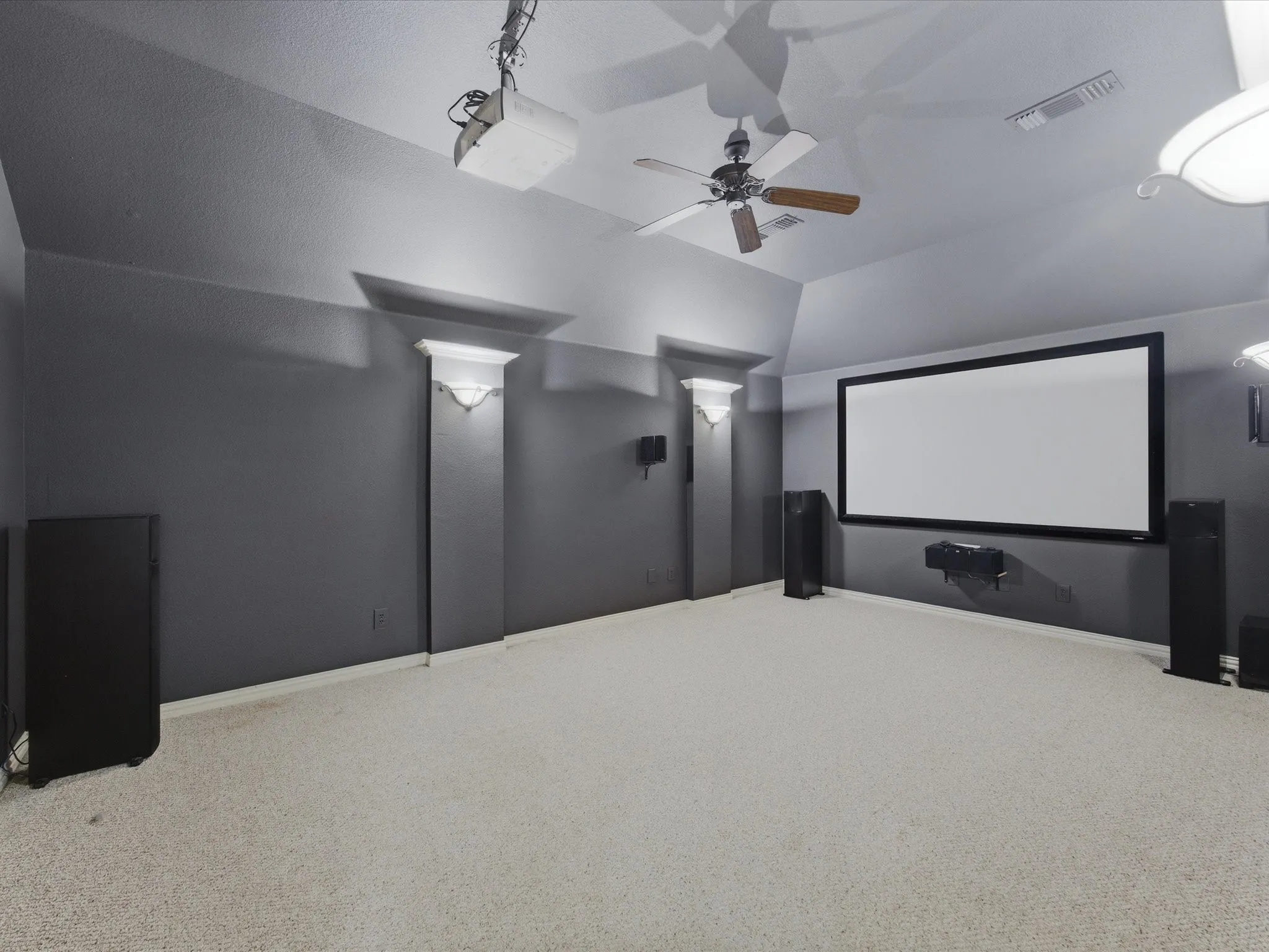 Dedicated media room featuring a large projection screen, projector, and integrated audio equipment