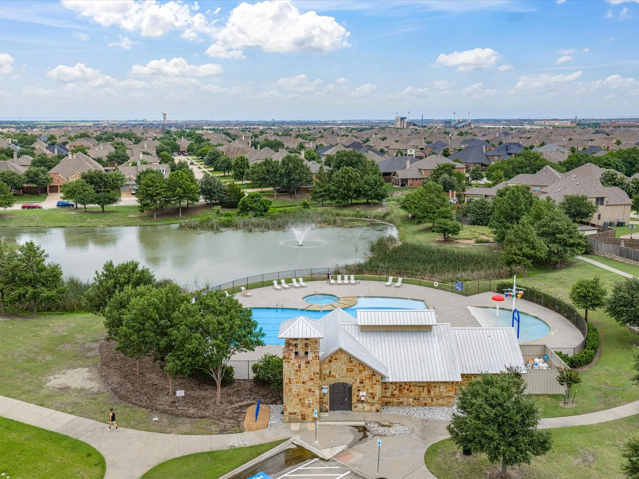 Community amenities featuring a stone and metal-roofed building, two swimming pools, lounge seating, and a water feature