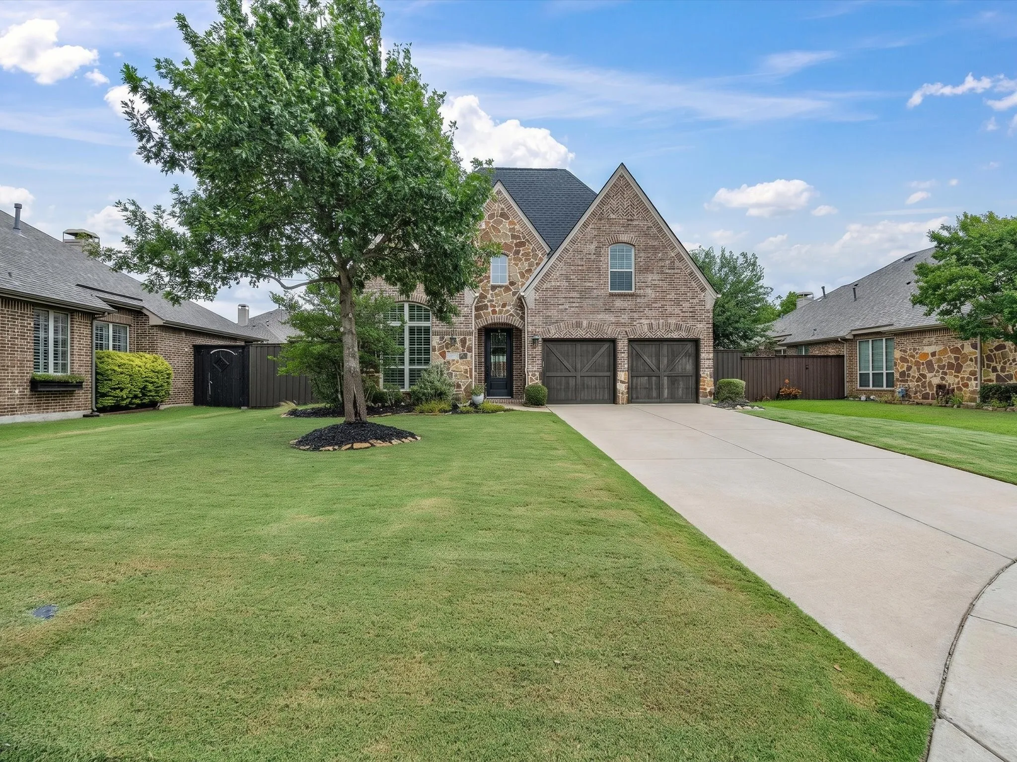 Stone veneer exterior featuring a two-car garage with wood-finish doors