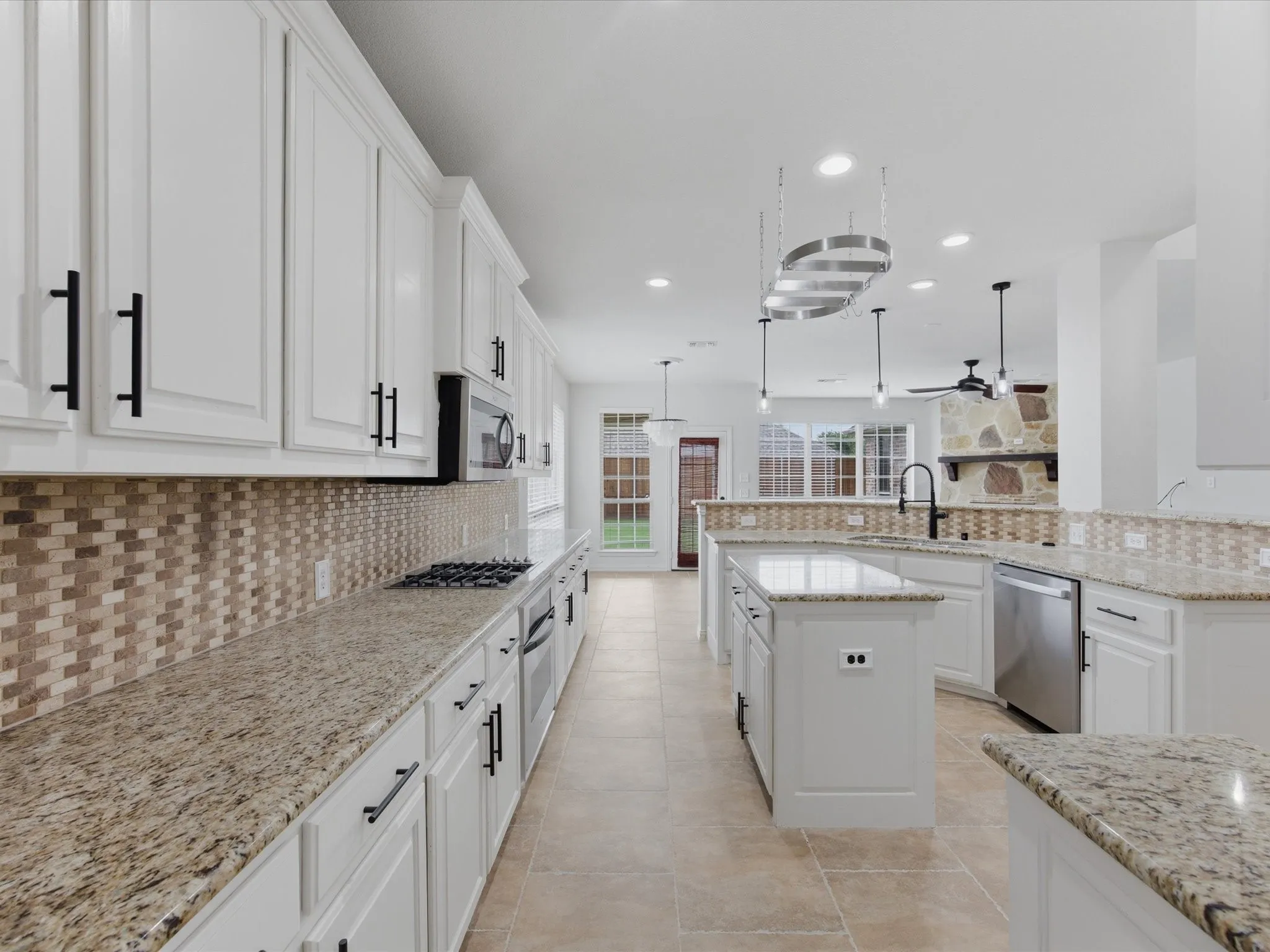 Spacious kitchen featuring white cabinetry, granite countertops, a mosaic tile backsplash, stainless steel appliances, and tile flooring
