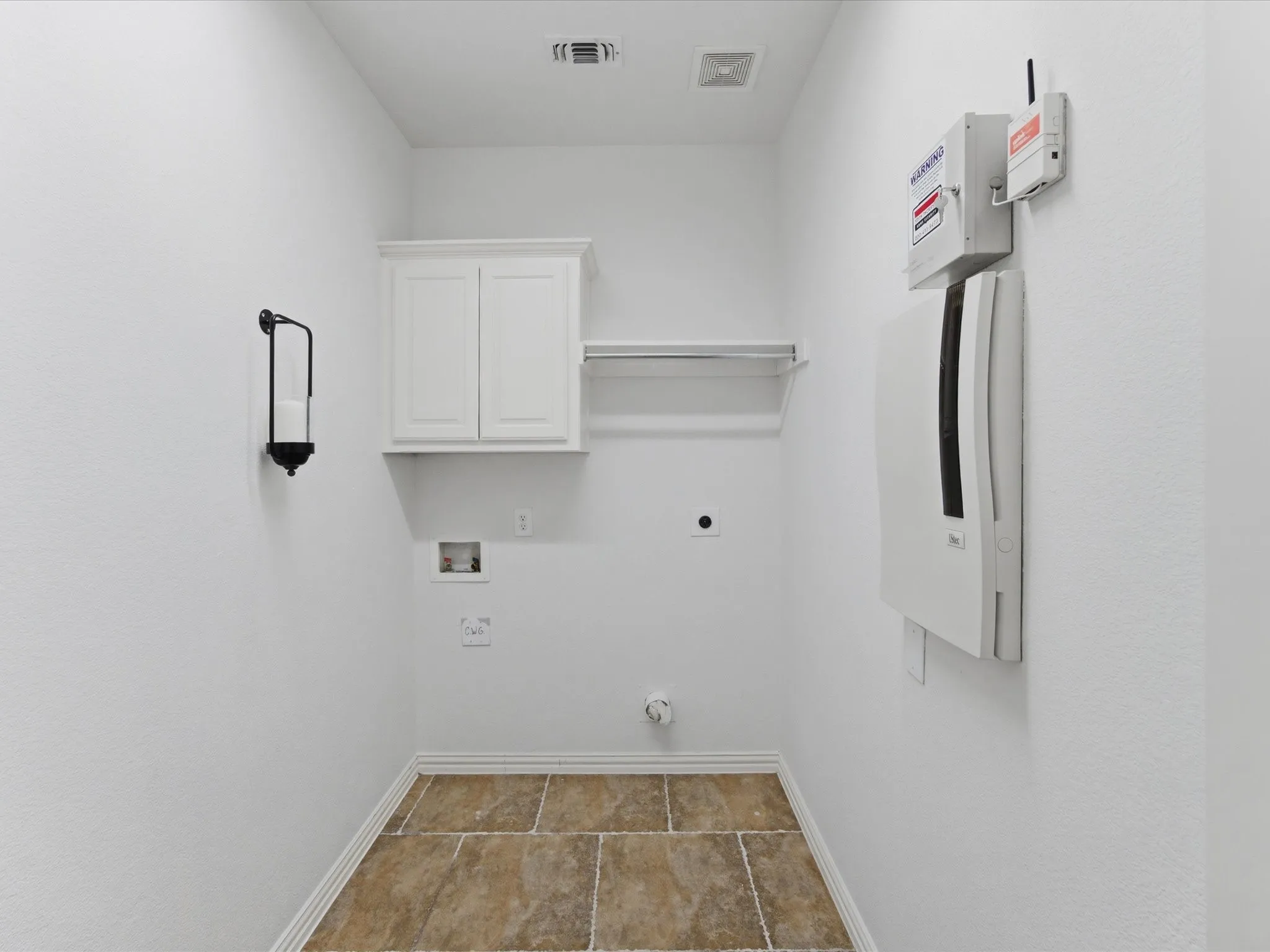 Laundry room featuring tiled flooring, a built-in white cabinet, a clothes hanging rod, and wall-mounted utilities